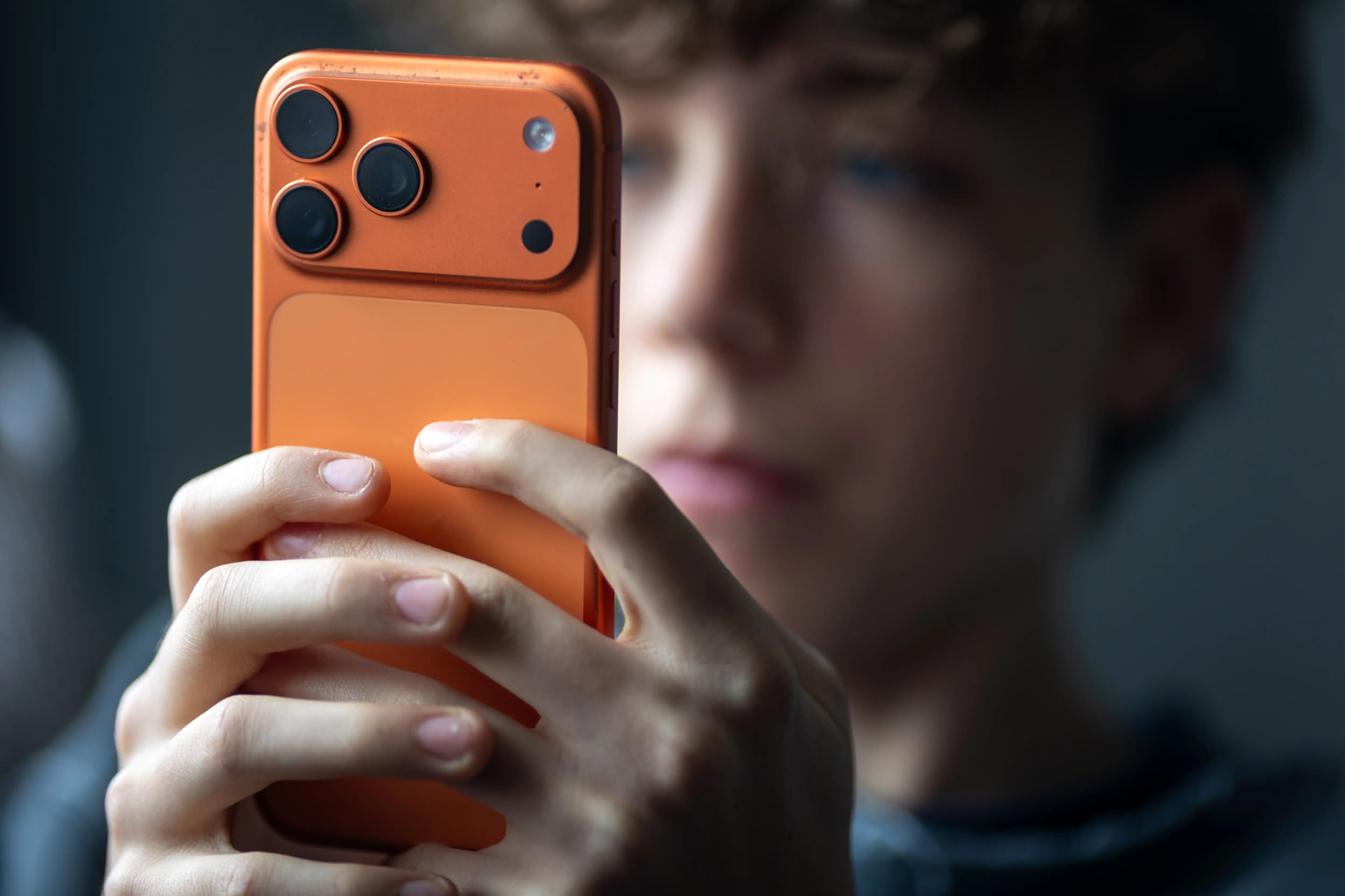 A child uses an orange iPhone.