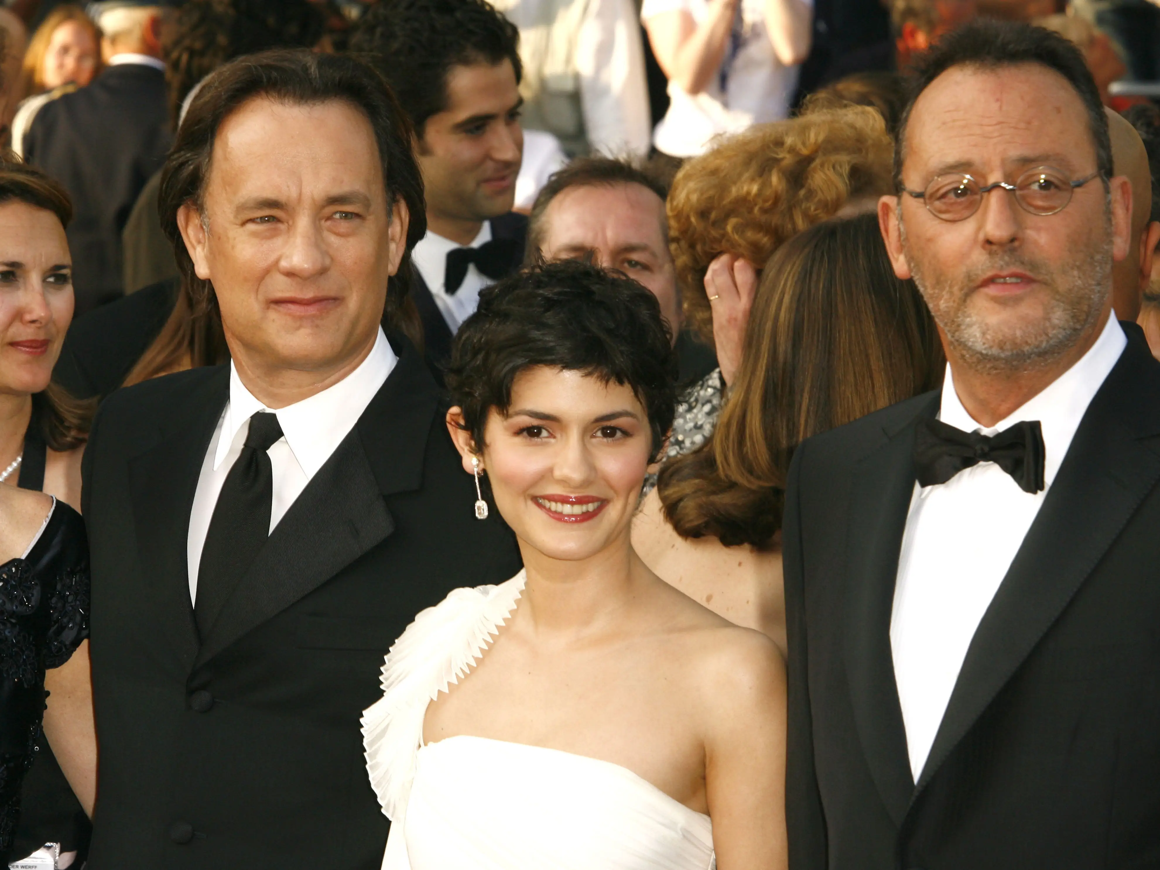 Two men in tuxes and a woman in a white dress pose for a photo.
