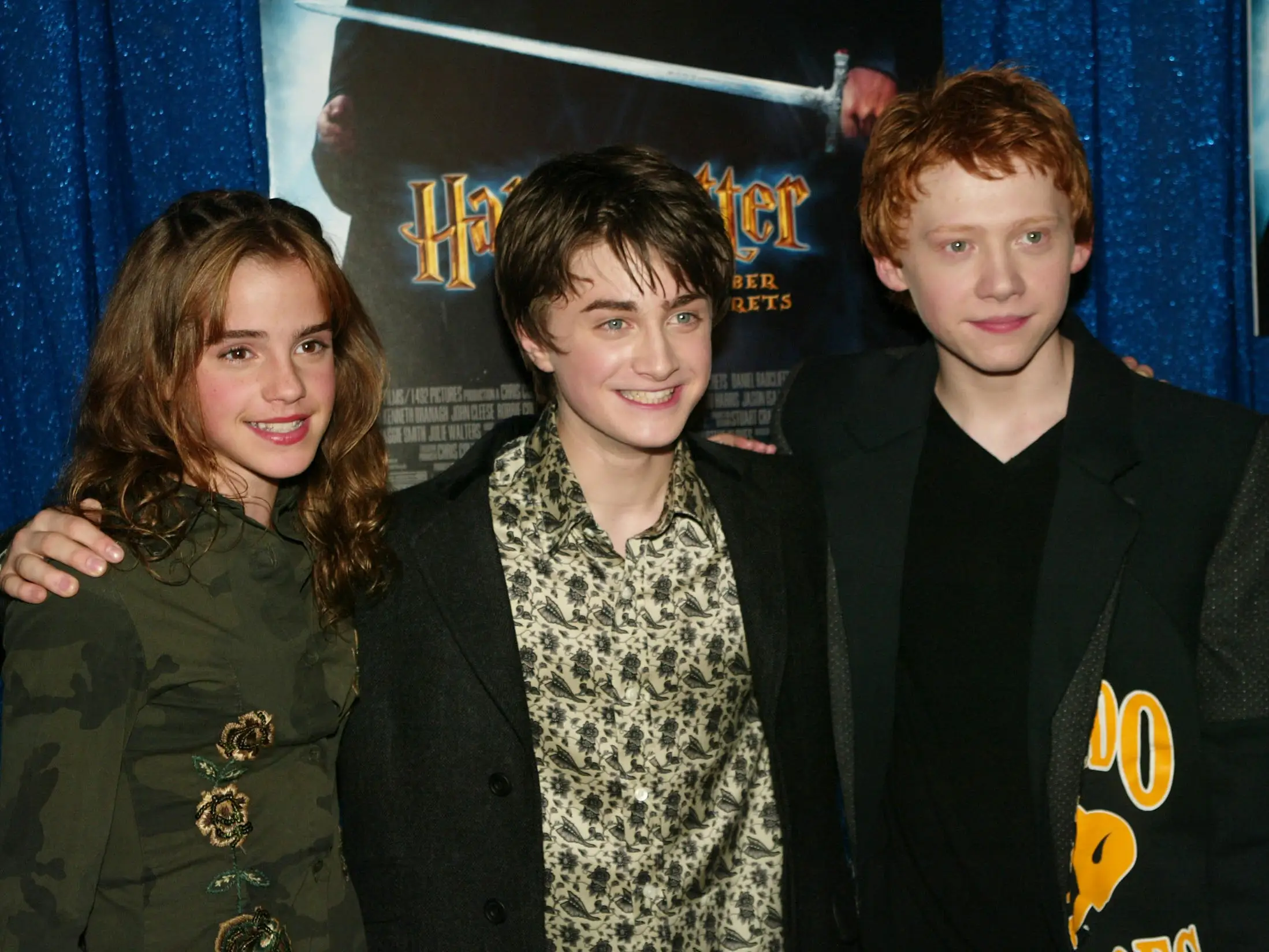 Three young people pose for a photo at a movie premiere.