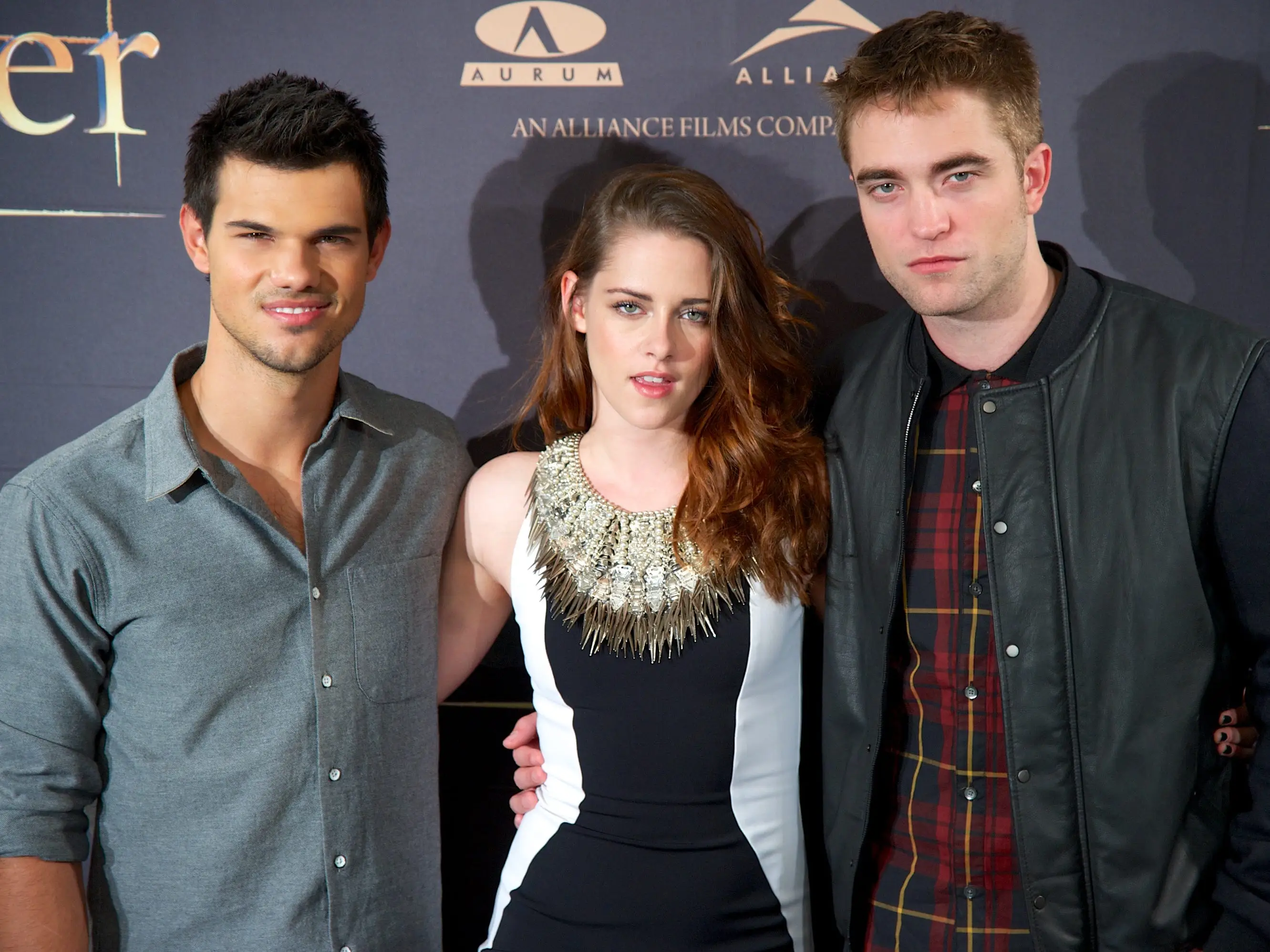 Three actors pose for a photo at a movie premiere.