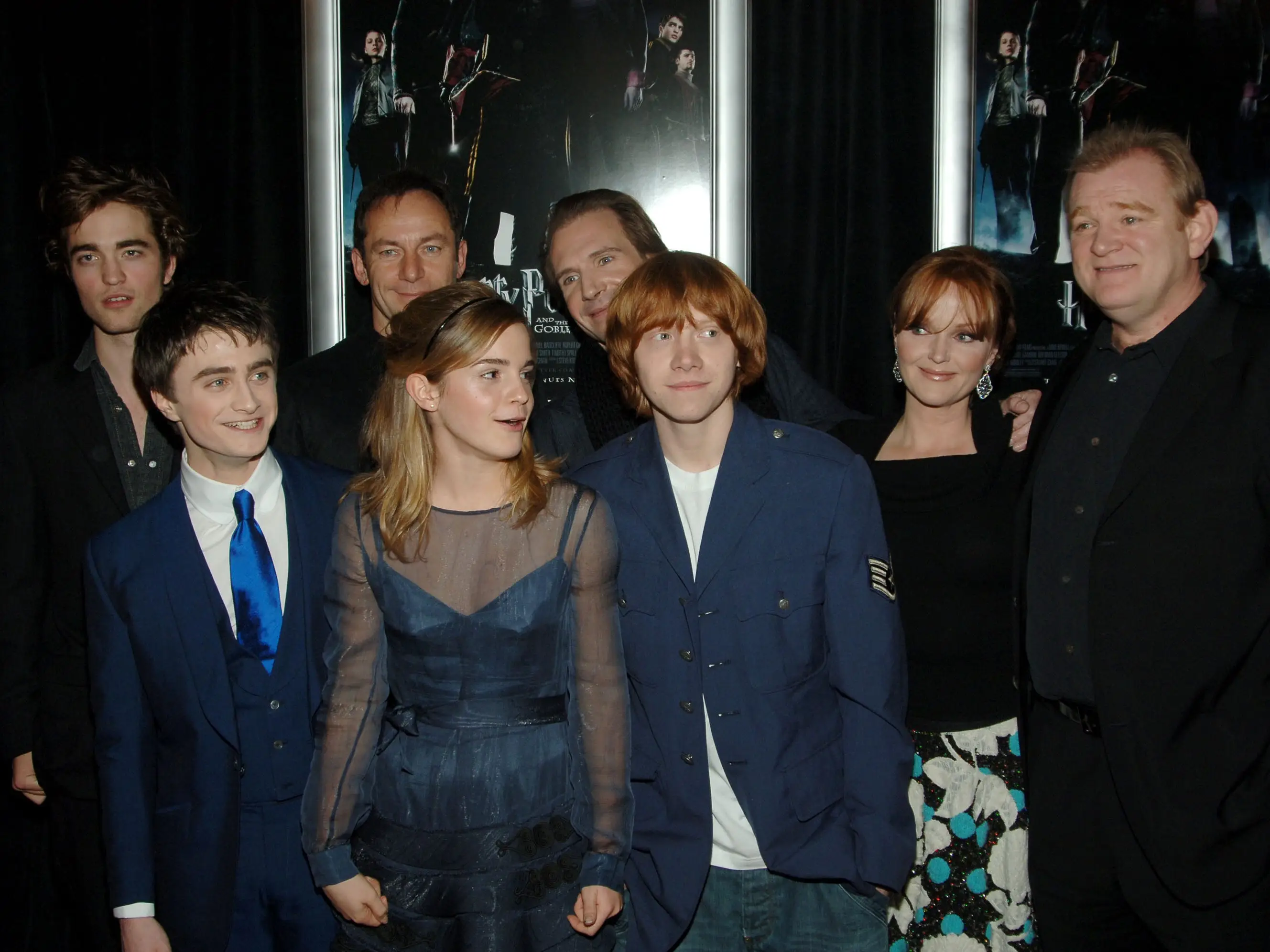 Several actors in dress attire pose for a photo at a movie premiere.