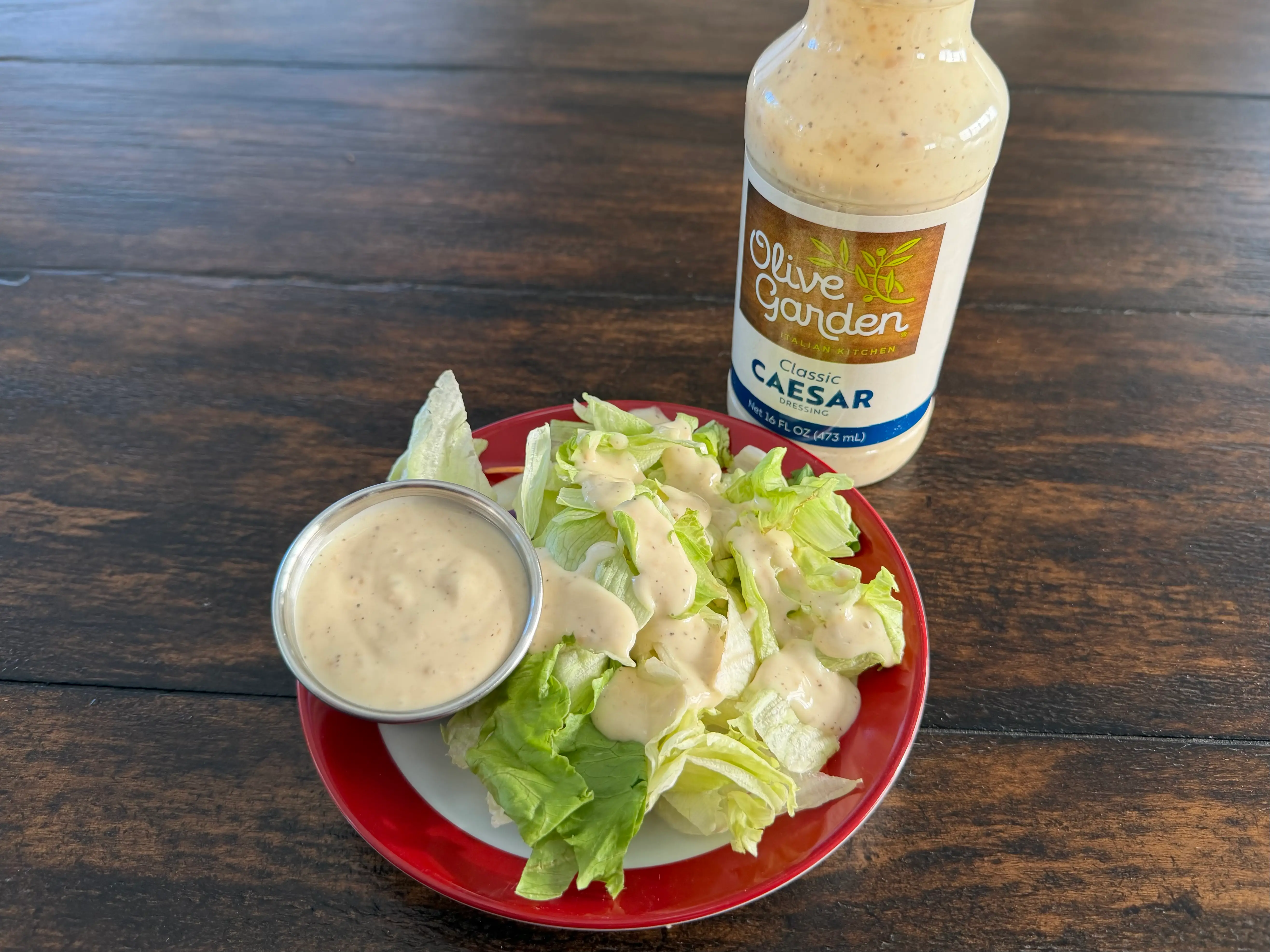 Olive Garden Caesar dressing bottle next to small salad