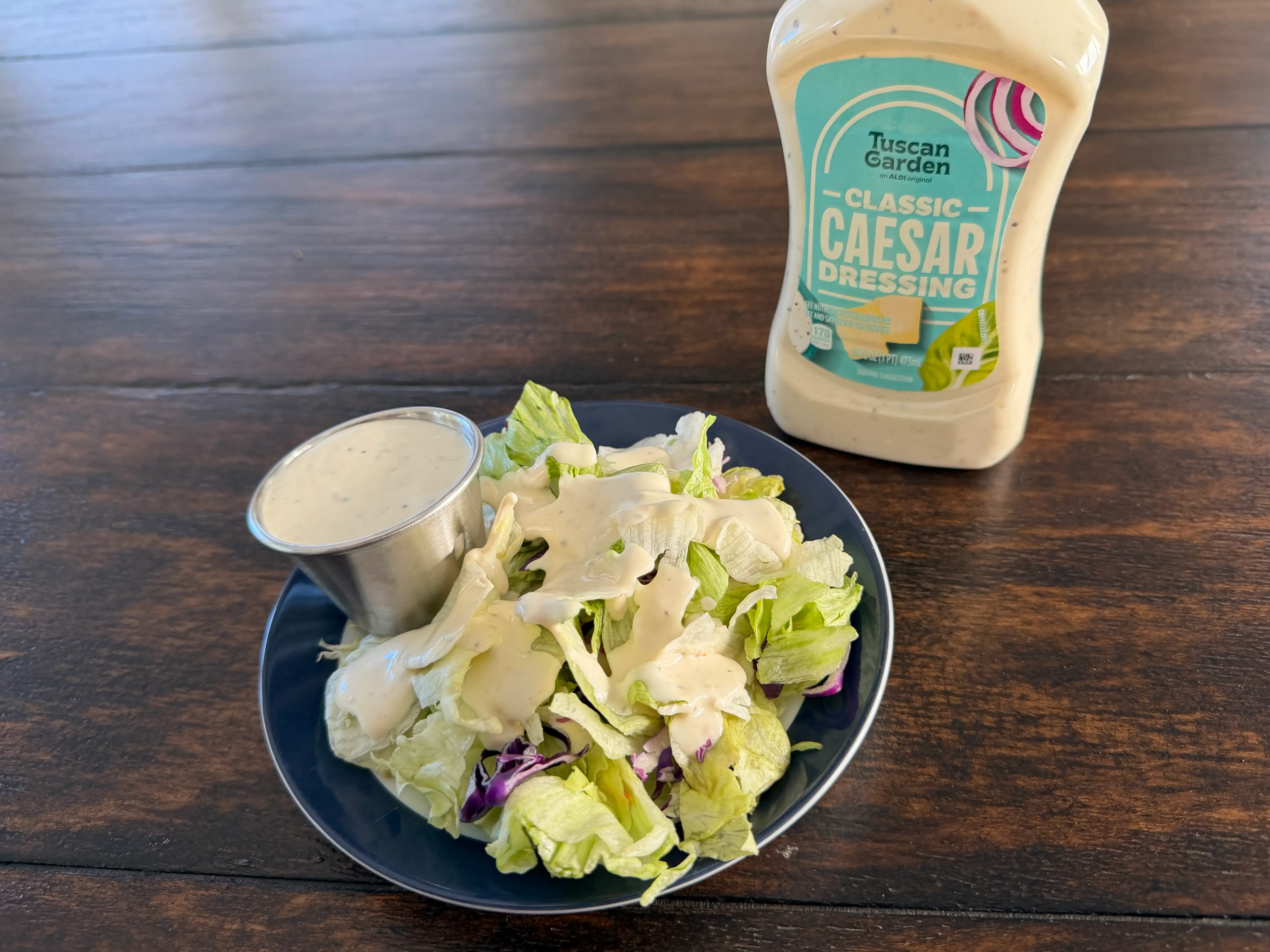 Tuscan Garden Caesar dressing bottle next to small salad