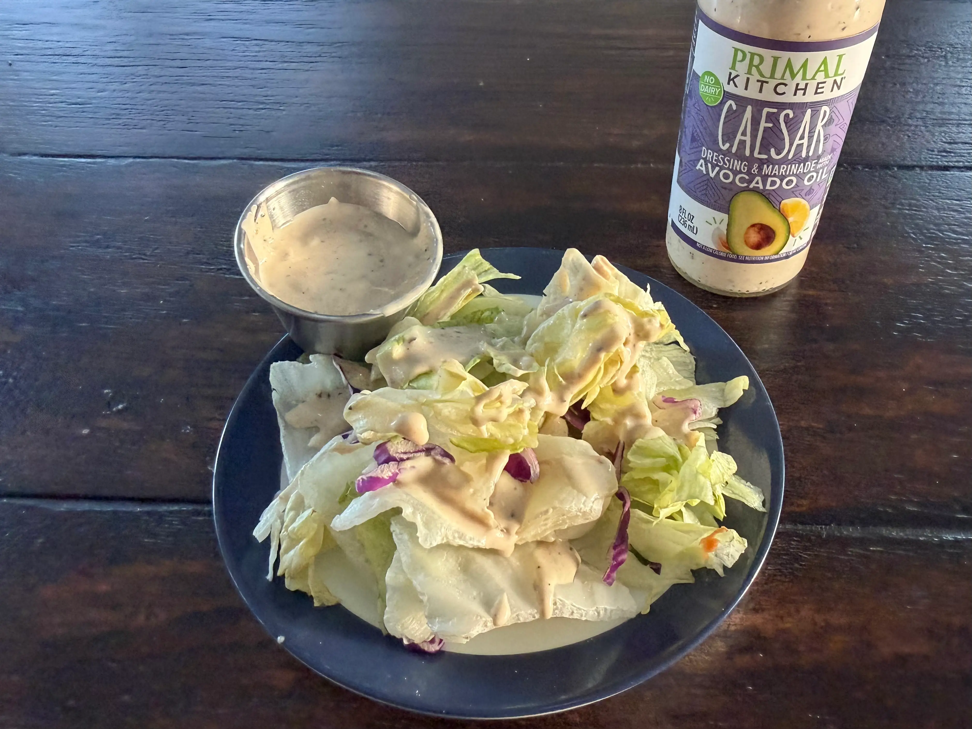 Primal Kitchen Caesar dressing bottle next to small salad