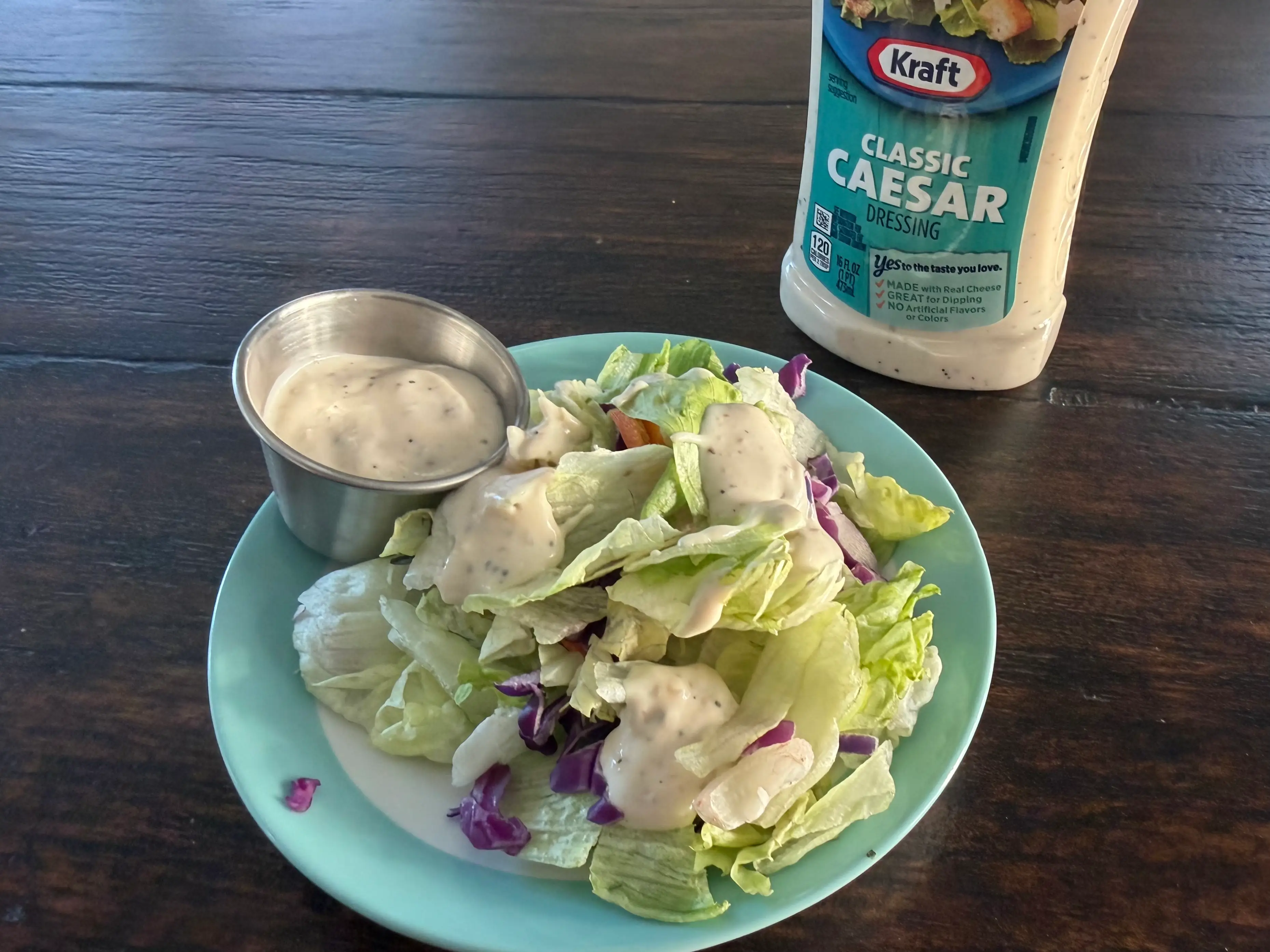 Kraft Caesar dressing bottle next to small salad