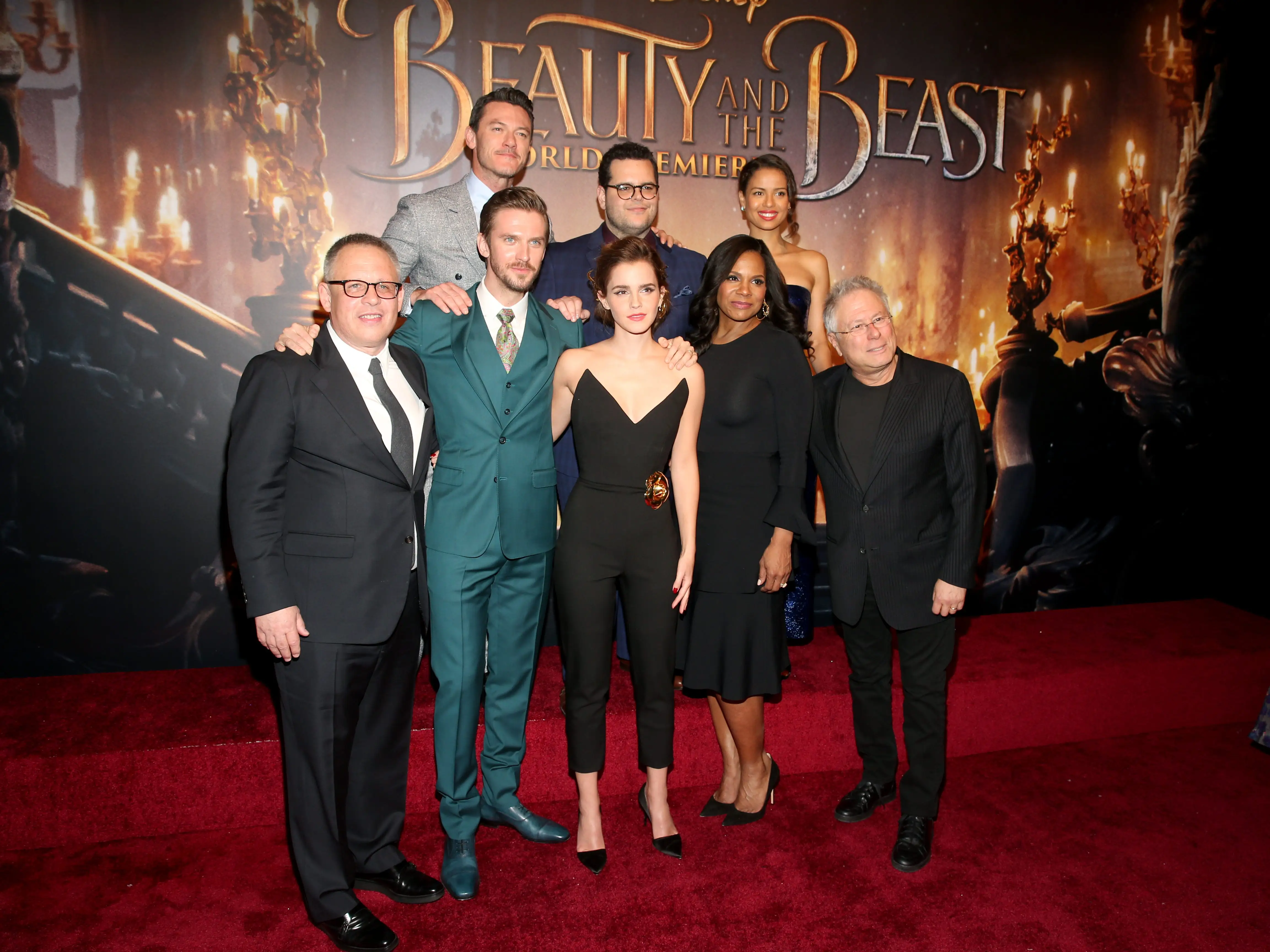 A cast of a movie stand before a movie poster on the red carpet.