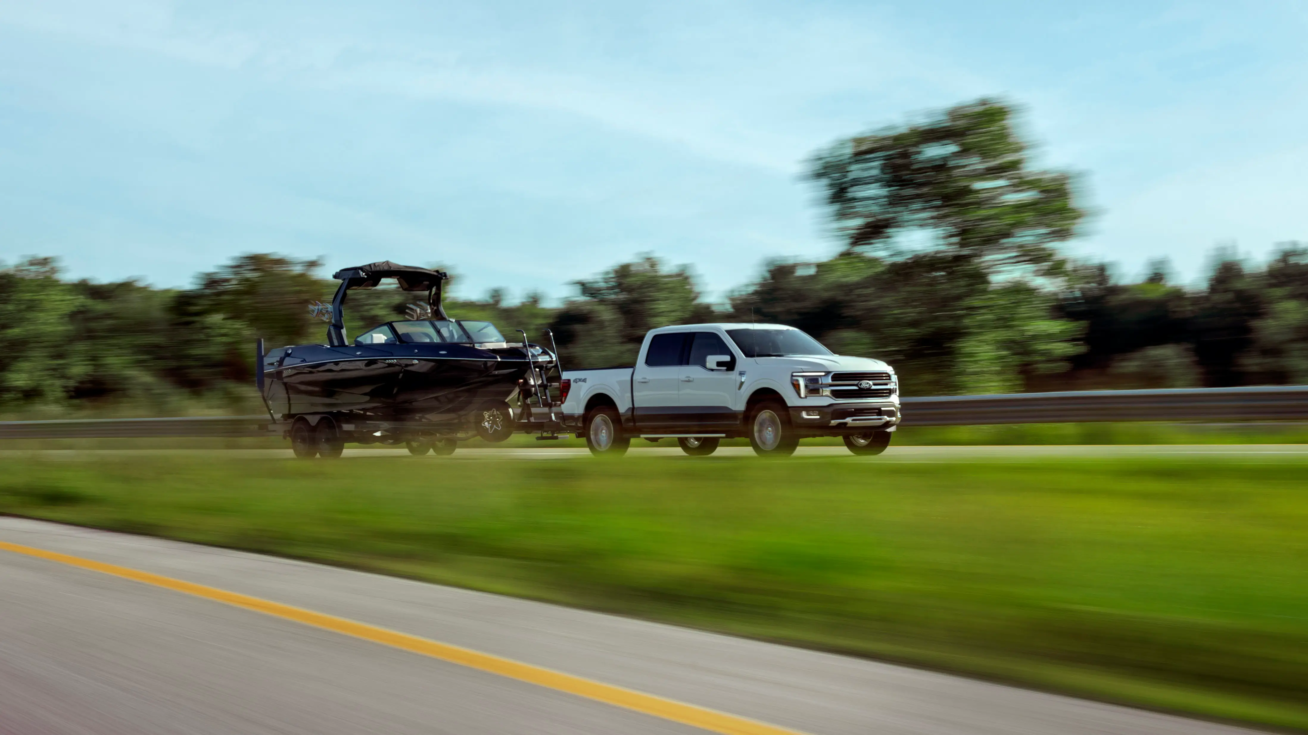 A white Ford F-150King Ranch towing a black boat.