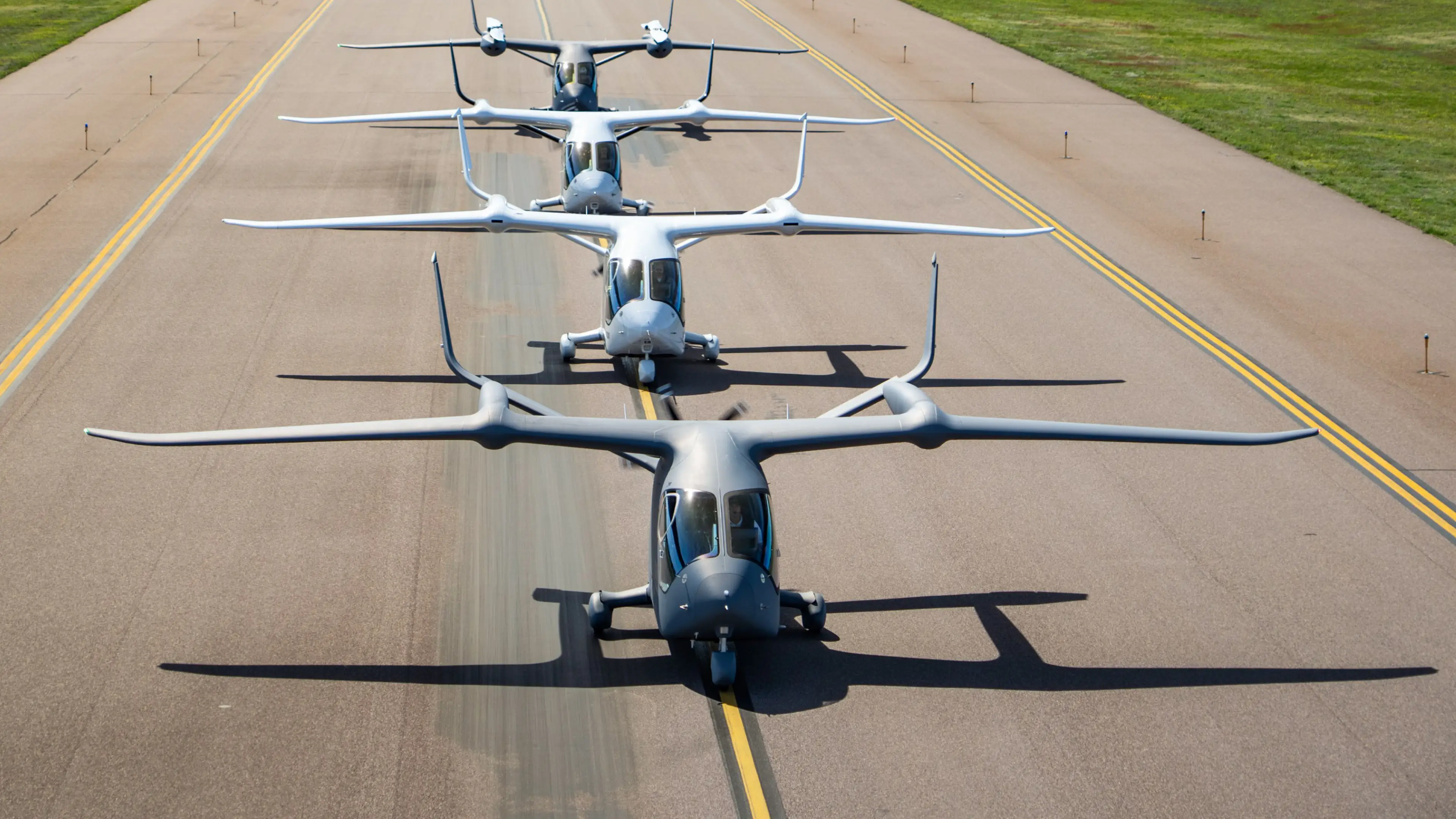 4 electric plane lined up on a runway