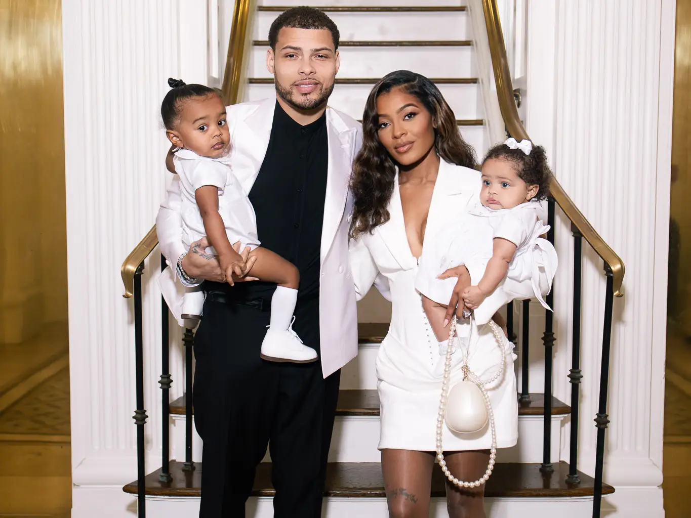 A family of four standing in front of a staircase.