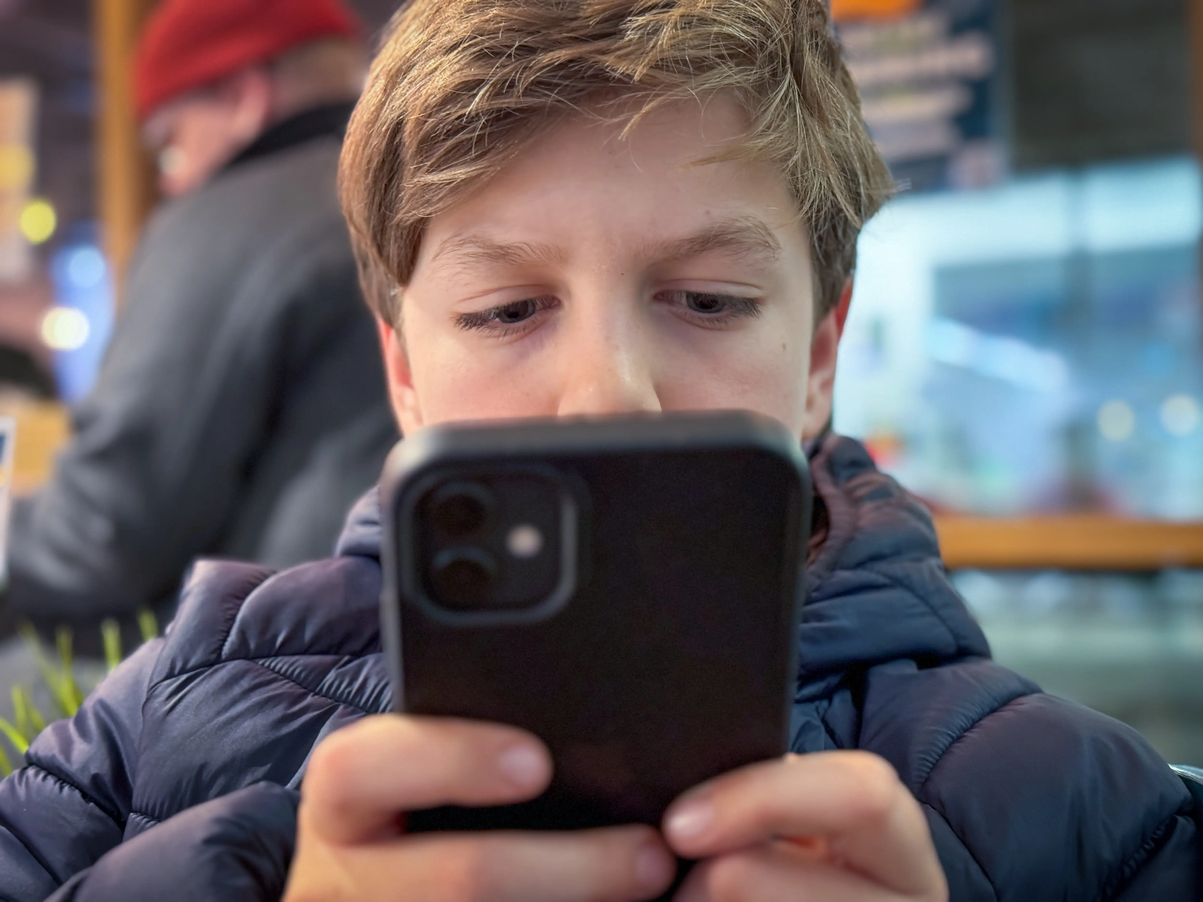 A child looks at an iPhone with a black phone case.