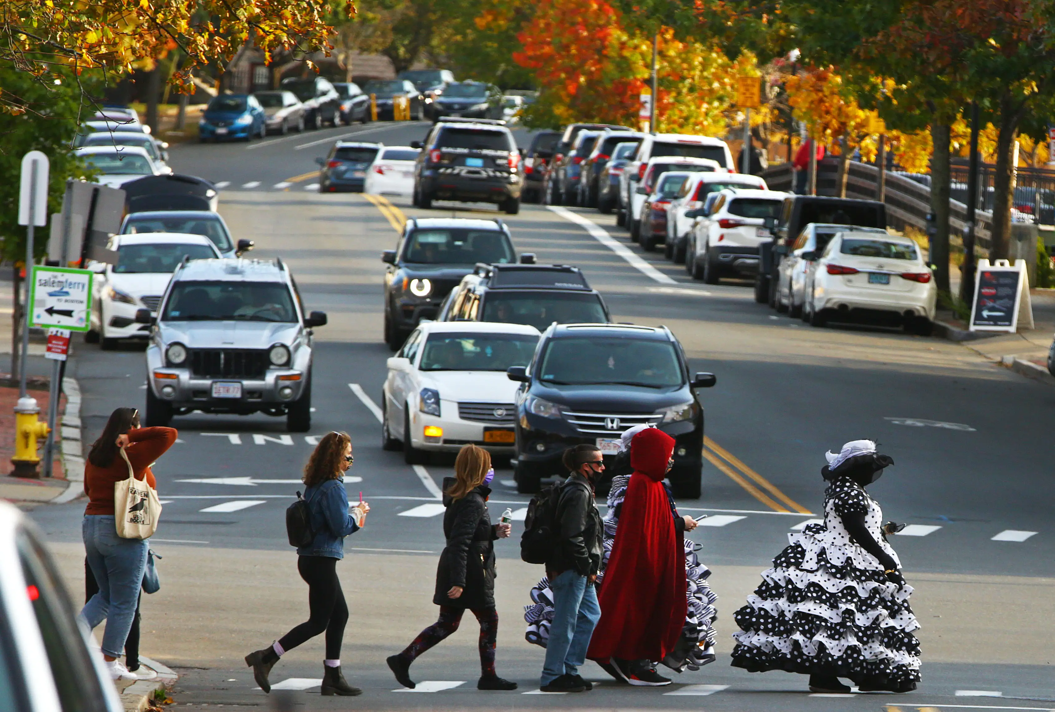 Pedestrians in costume and normal dress cross the street in Salem,