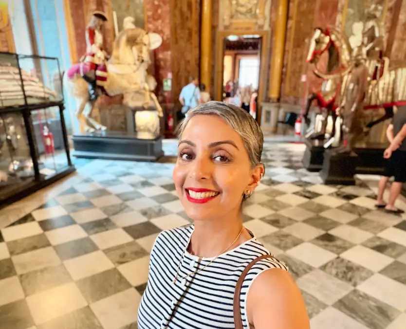 The writer posing at an armory museum in Turin, Italy, with statues in the background.