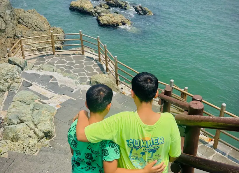 The writer's sons walking down a staircase to water in Busan, with their arms wrapped around each other.