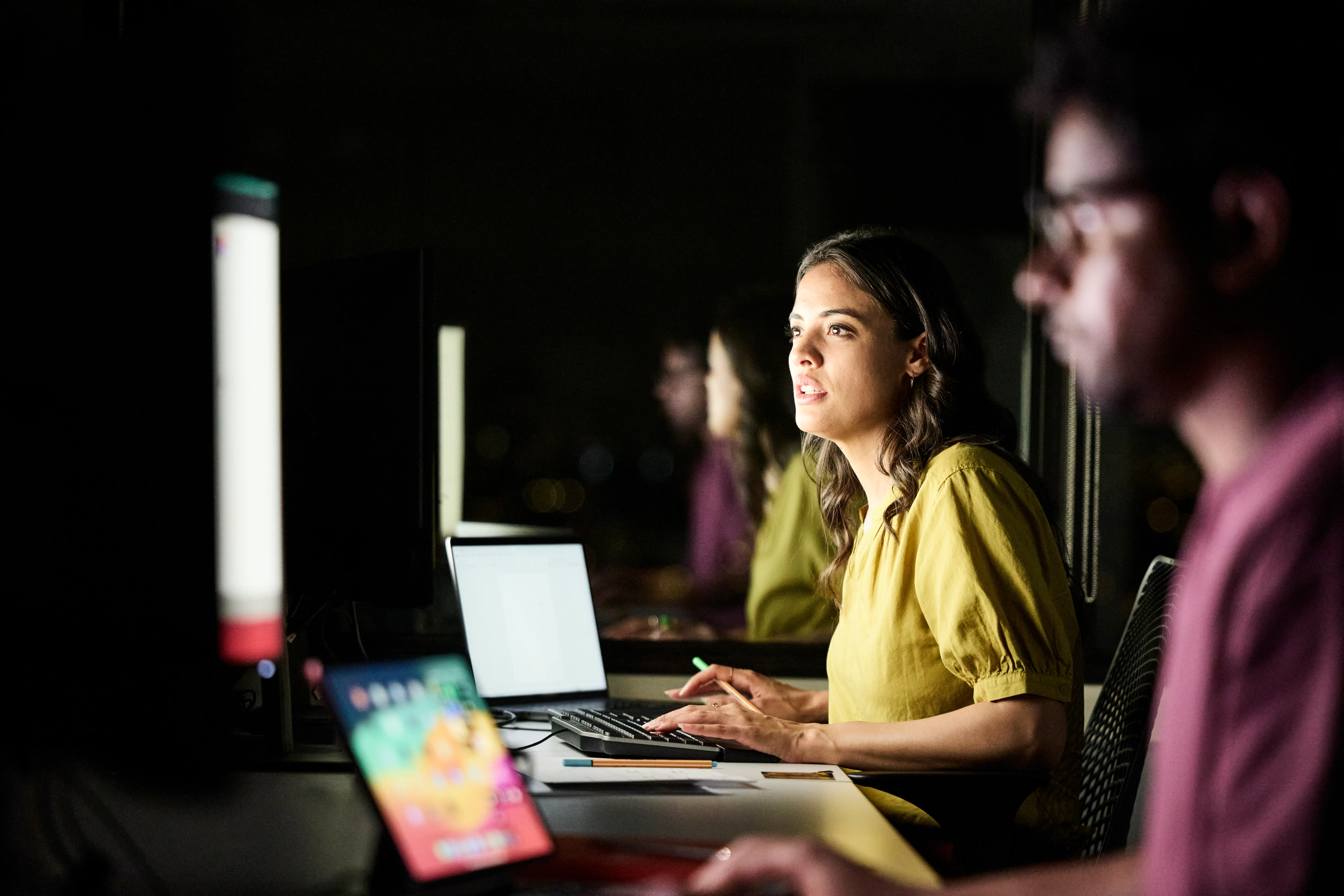 A woman sits in front of an illuminated screen
