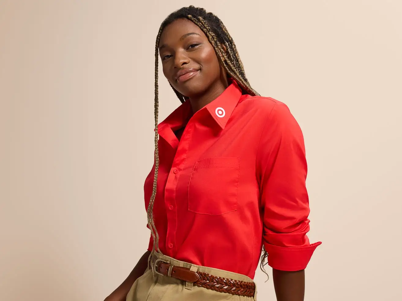 Person in a red Target-collared shirt poses against a beige studio background.