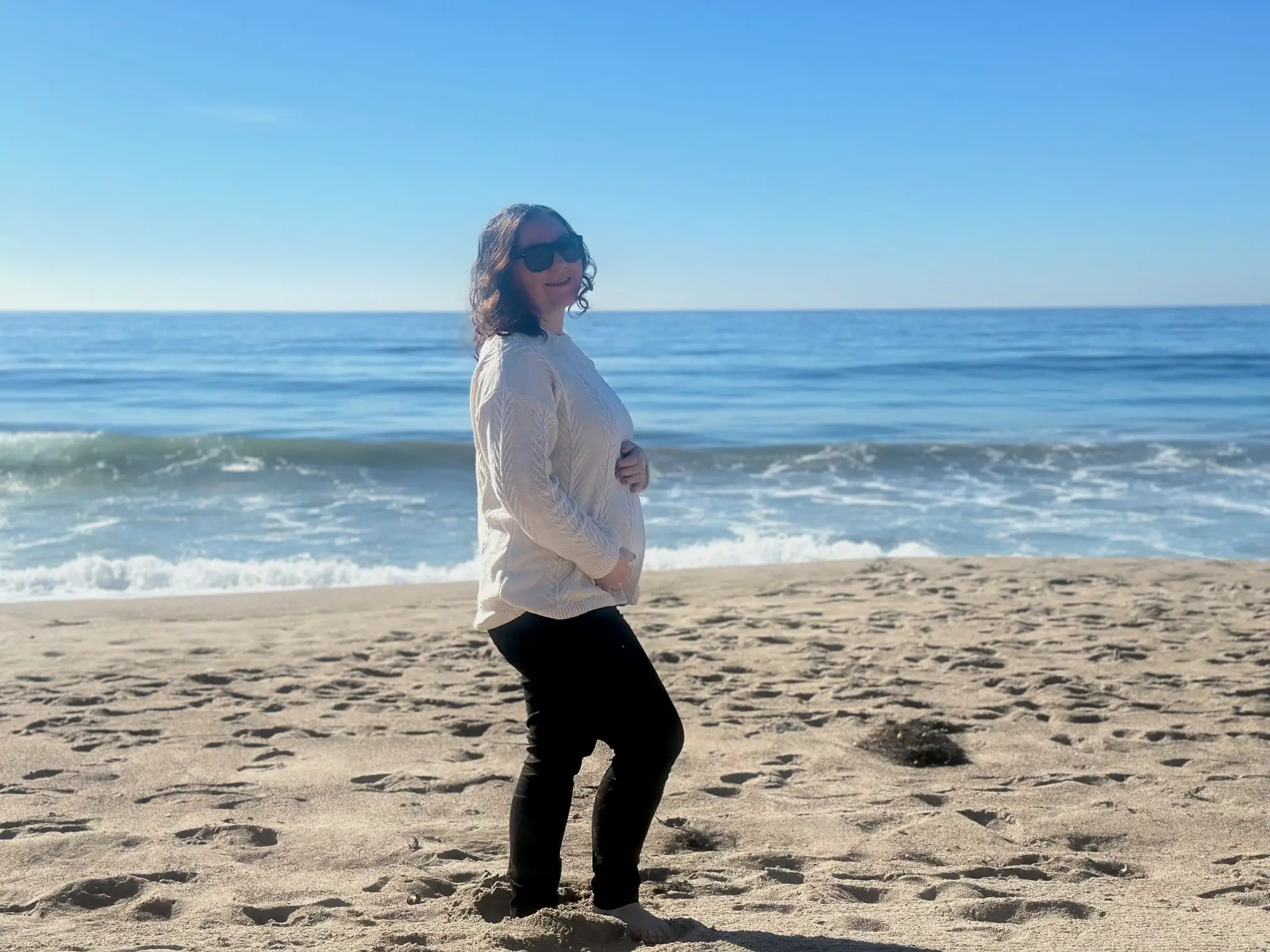 The author poses while pregnant on a beach.