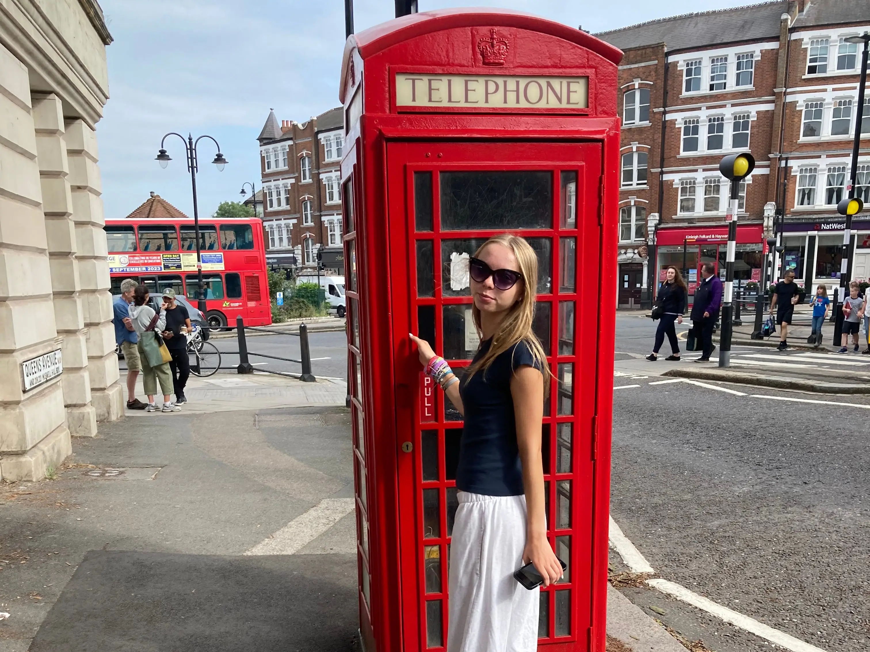 A teenager standing outside a phone box in London.