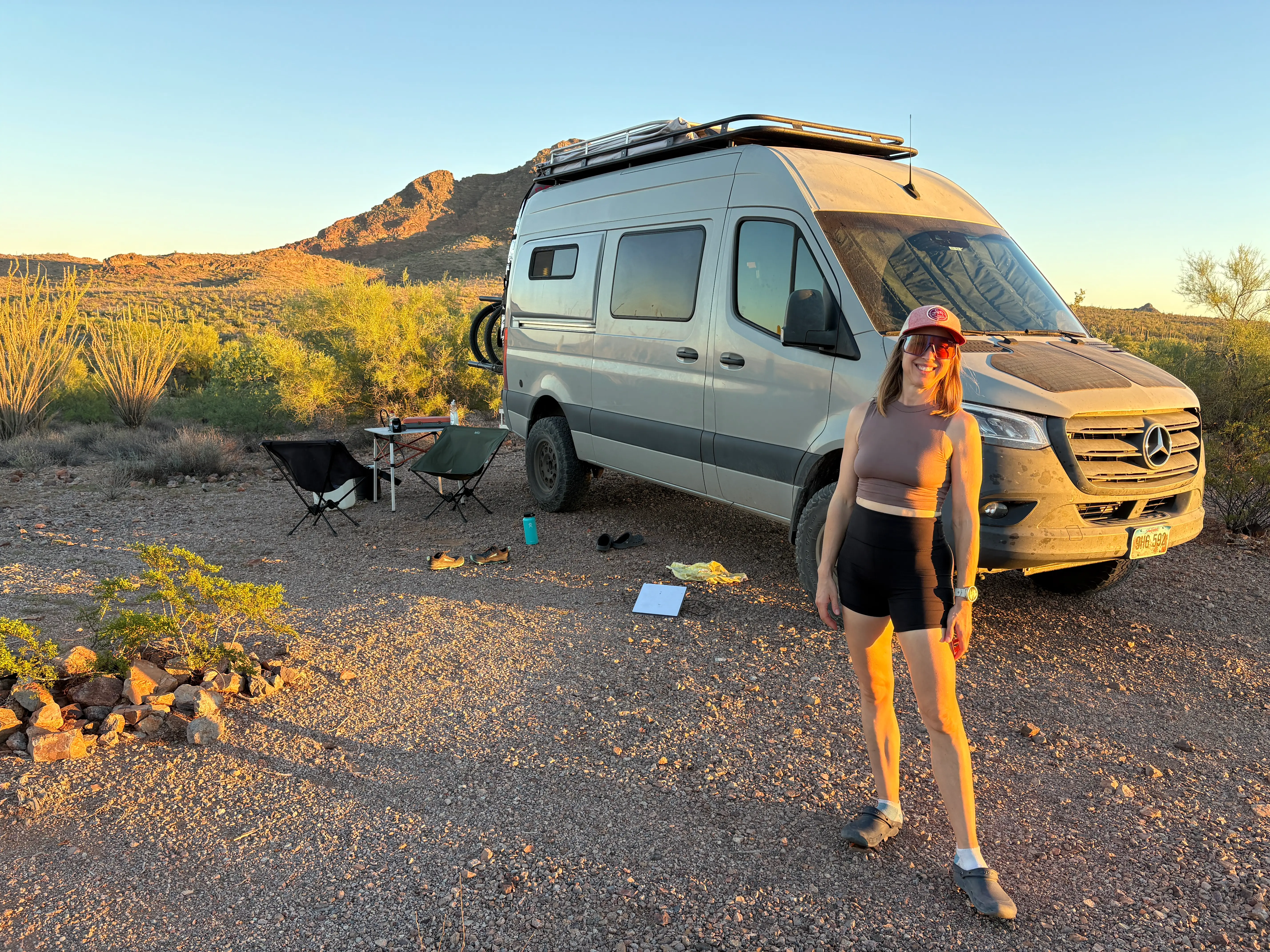 Woman in sand with camper van behind her