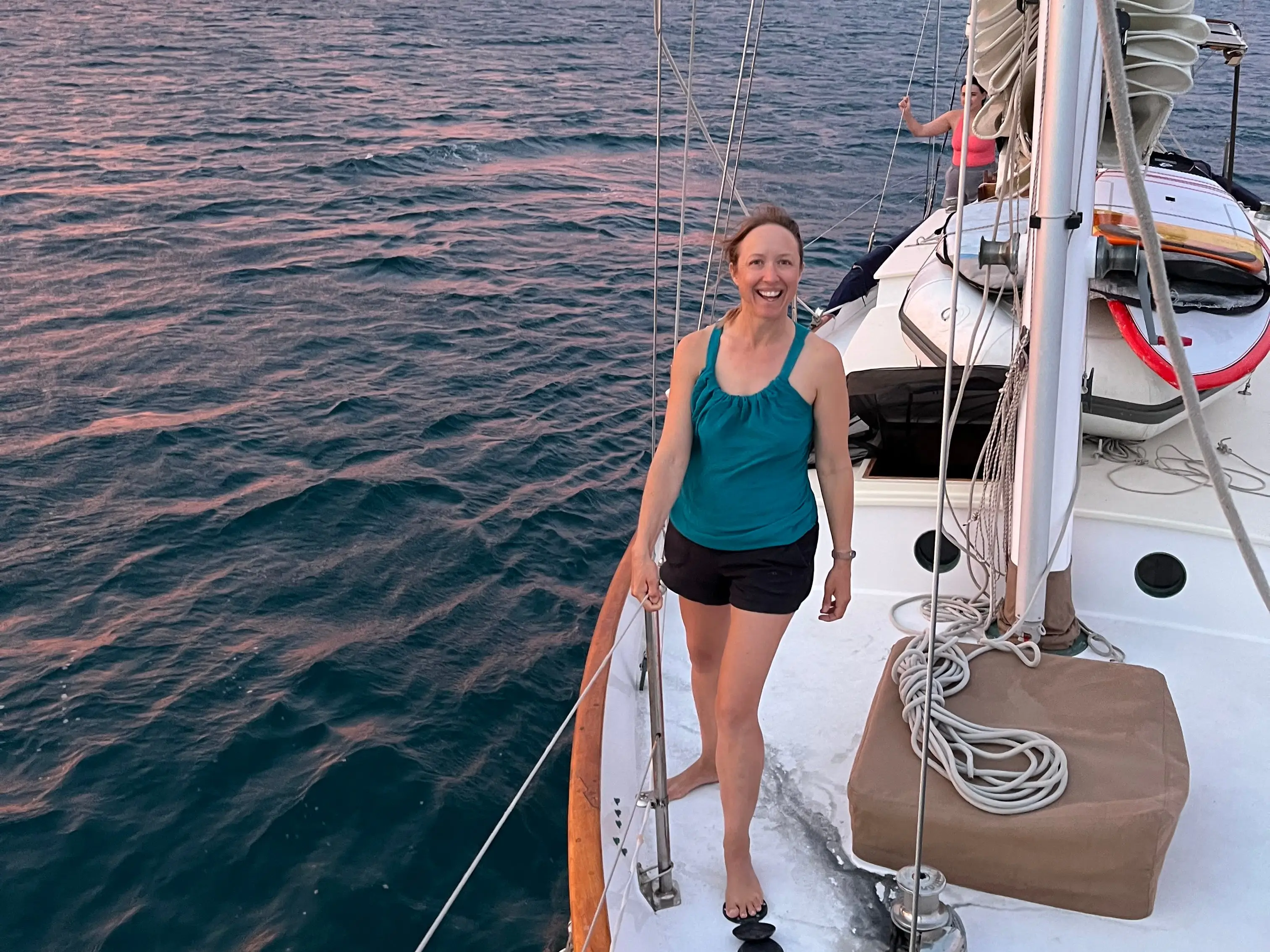 Woman standing on sailboat with pinkish skies behind