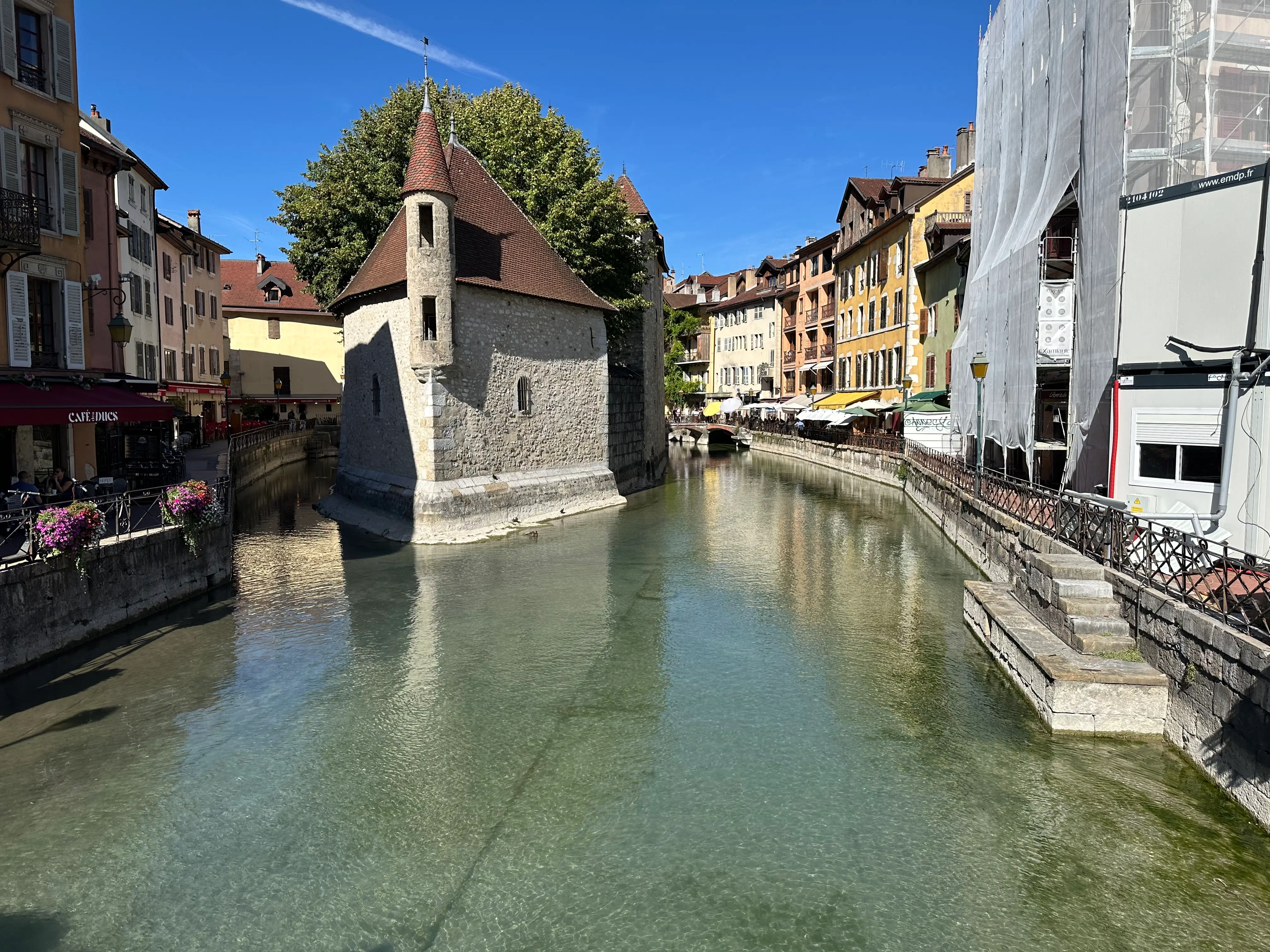 Palais de l'Île stands in a canal bordered by colorful historic buildings under a clear blue sky.