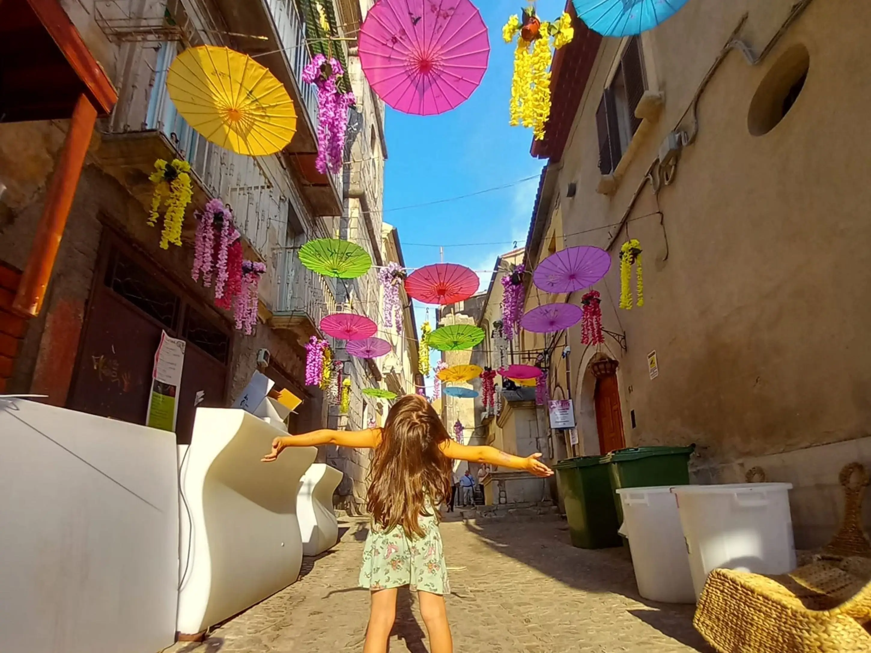 The author's daughter poses under umbrellas lining a street in Italy.