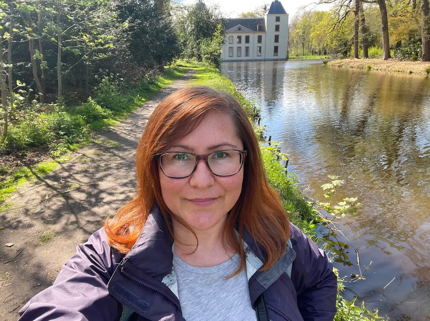 The writer stands near a small river, with a castle visible in the background, in Warmond, a town in the Netherlands.