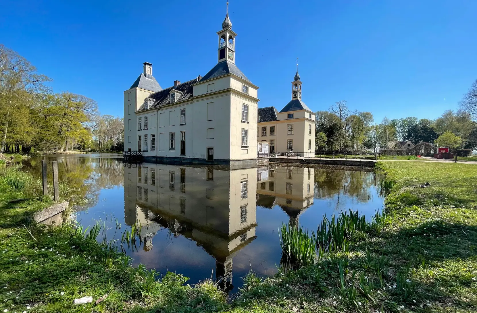 Huys te Warmont, a historic country estate with a moat, surrounded by water and grass.
