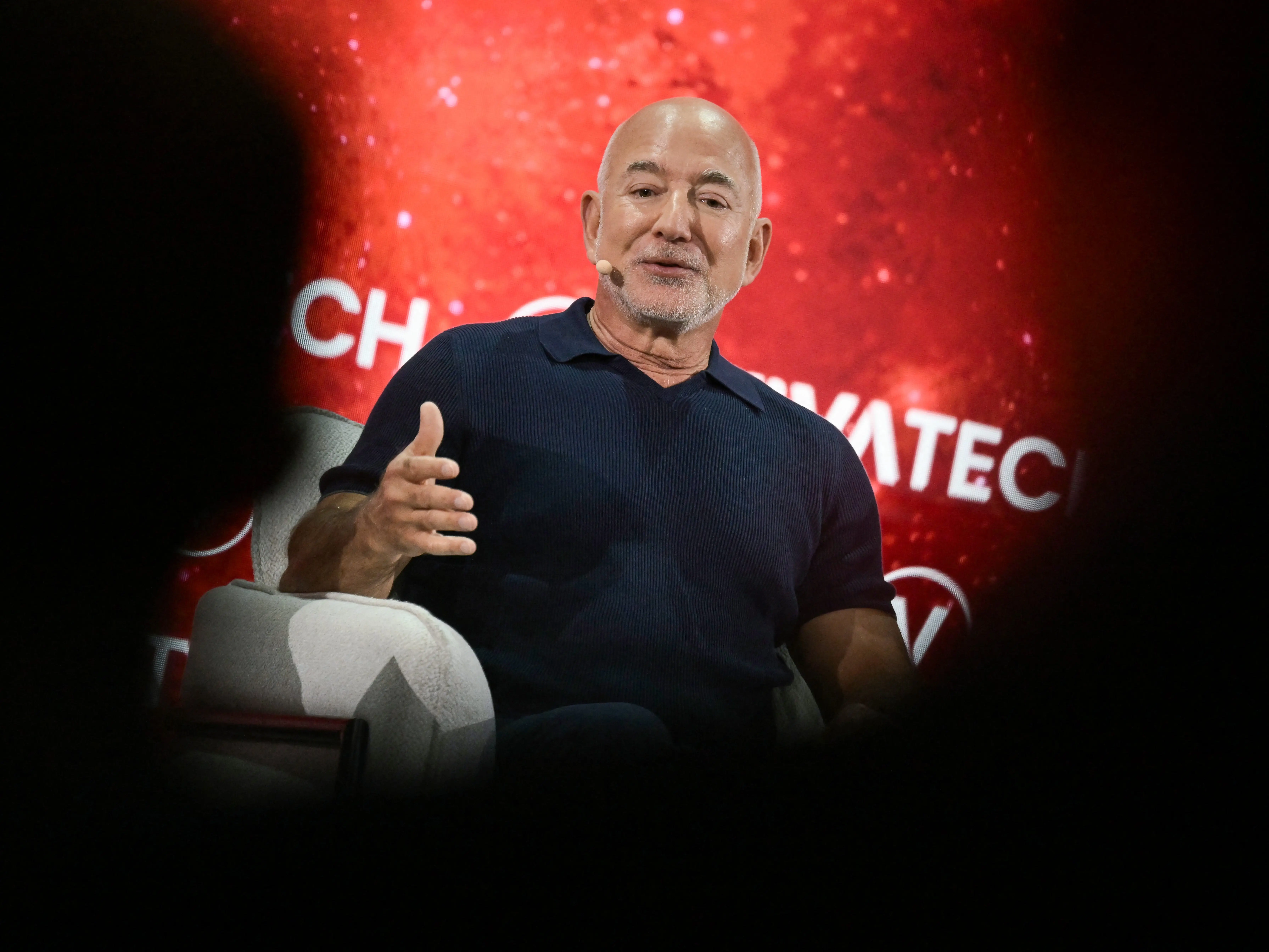 A man in a blue shirt speaks to a crowd.