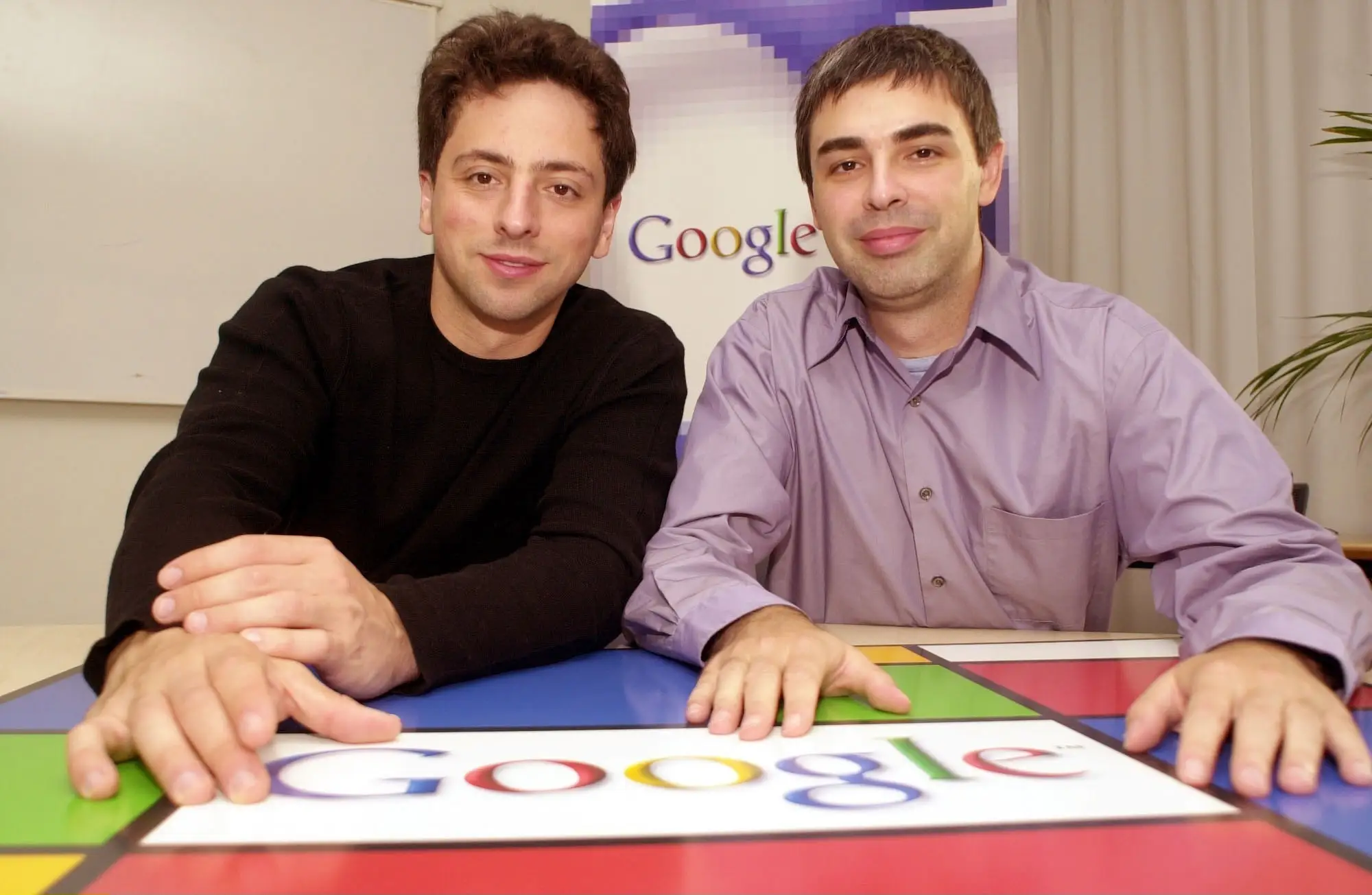 Two men sitting down pose for a camera.