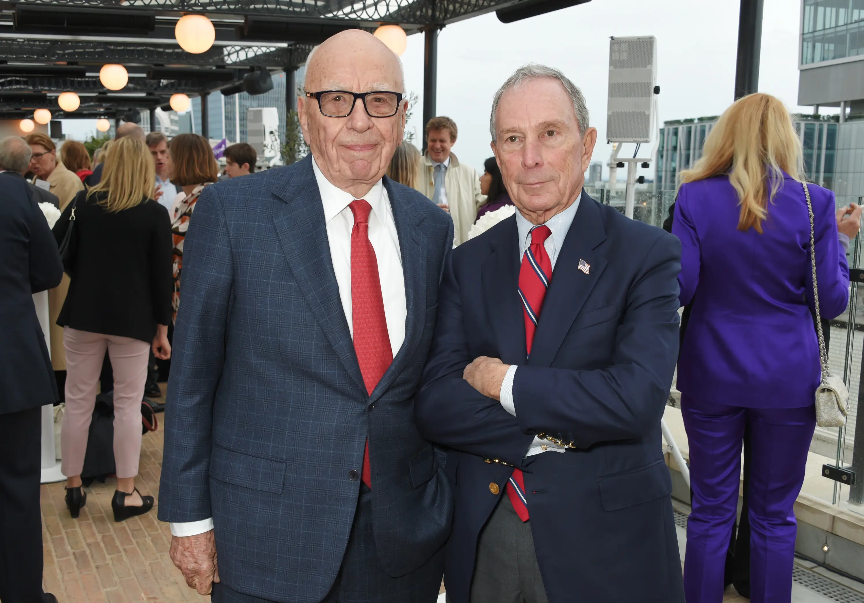 Two men in tuxedos pose before a camera.