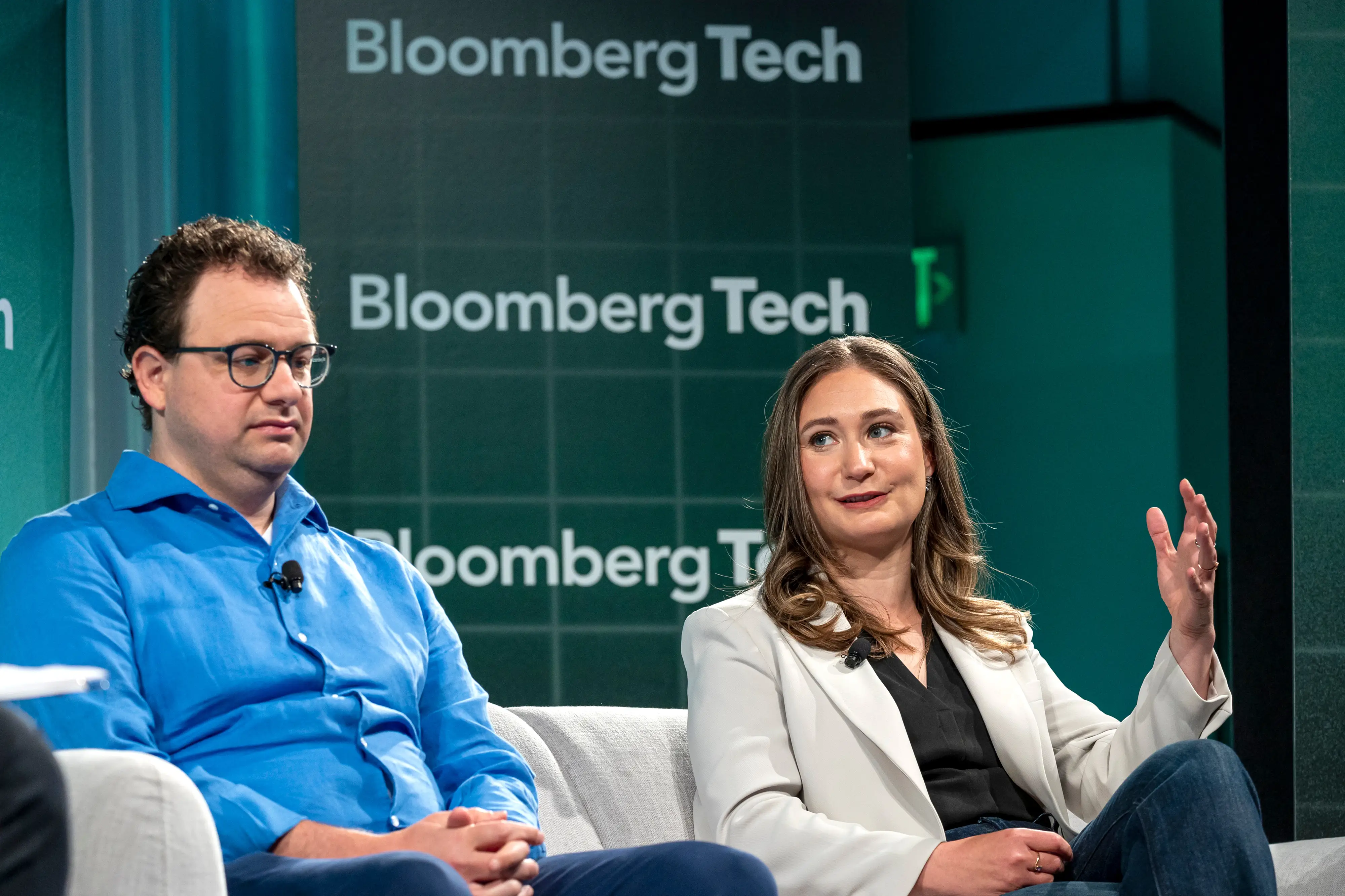 Two panelists sit onstage before a green BloombergTech backdrop during a technology event.