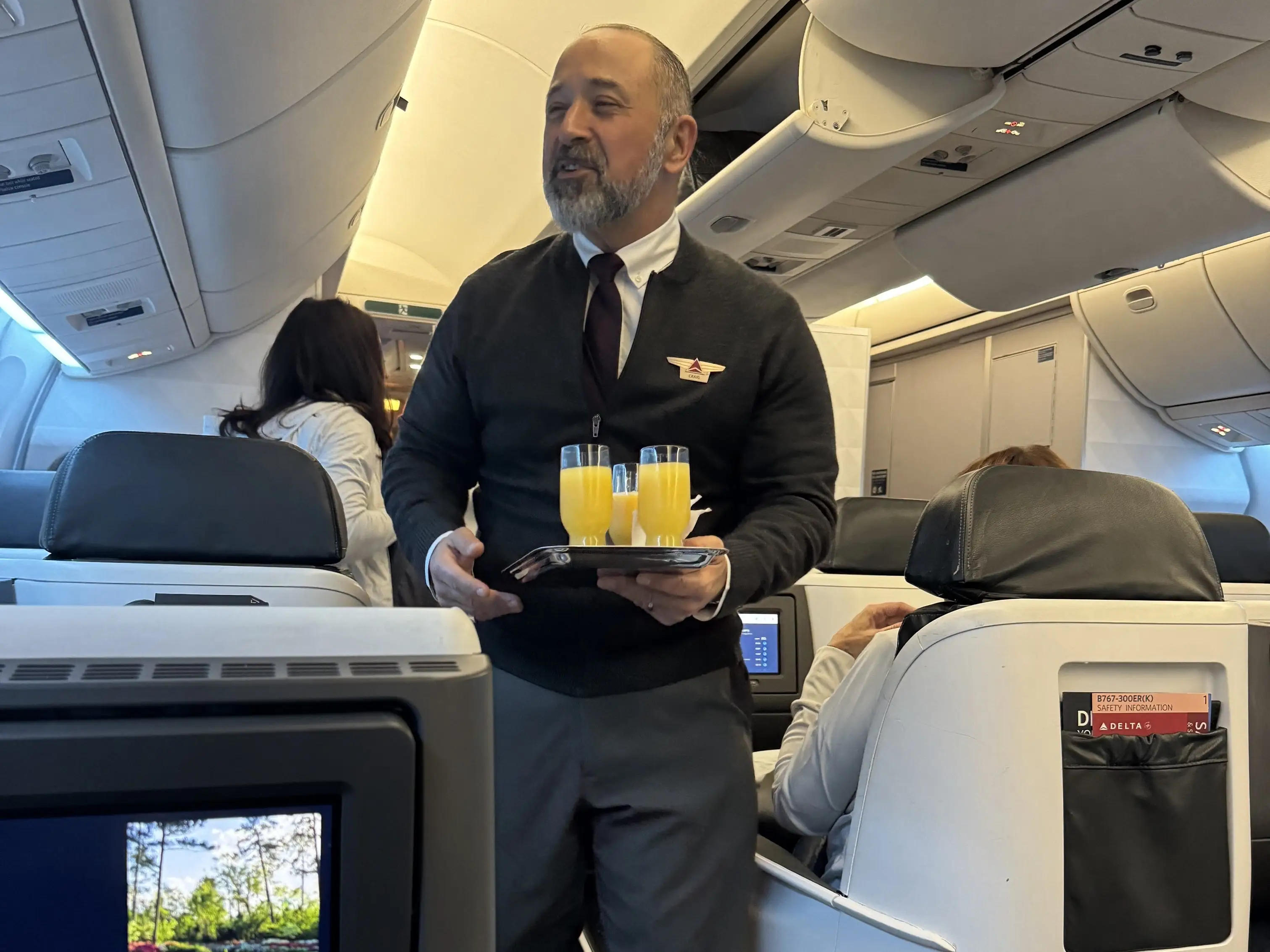 A flight attendant serving orange juice aboard a flight.