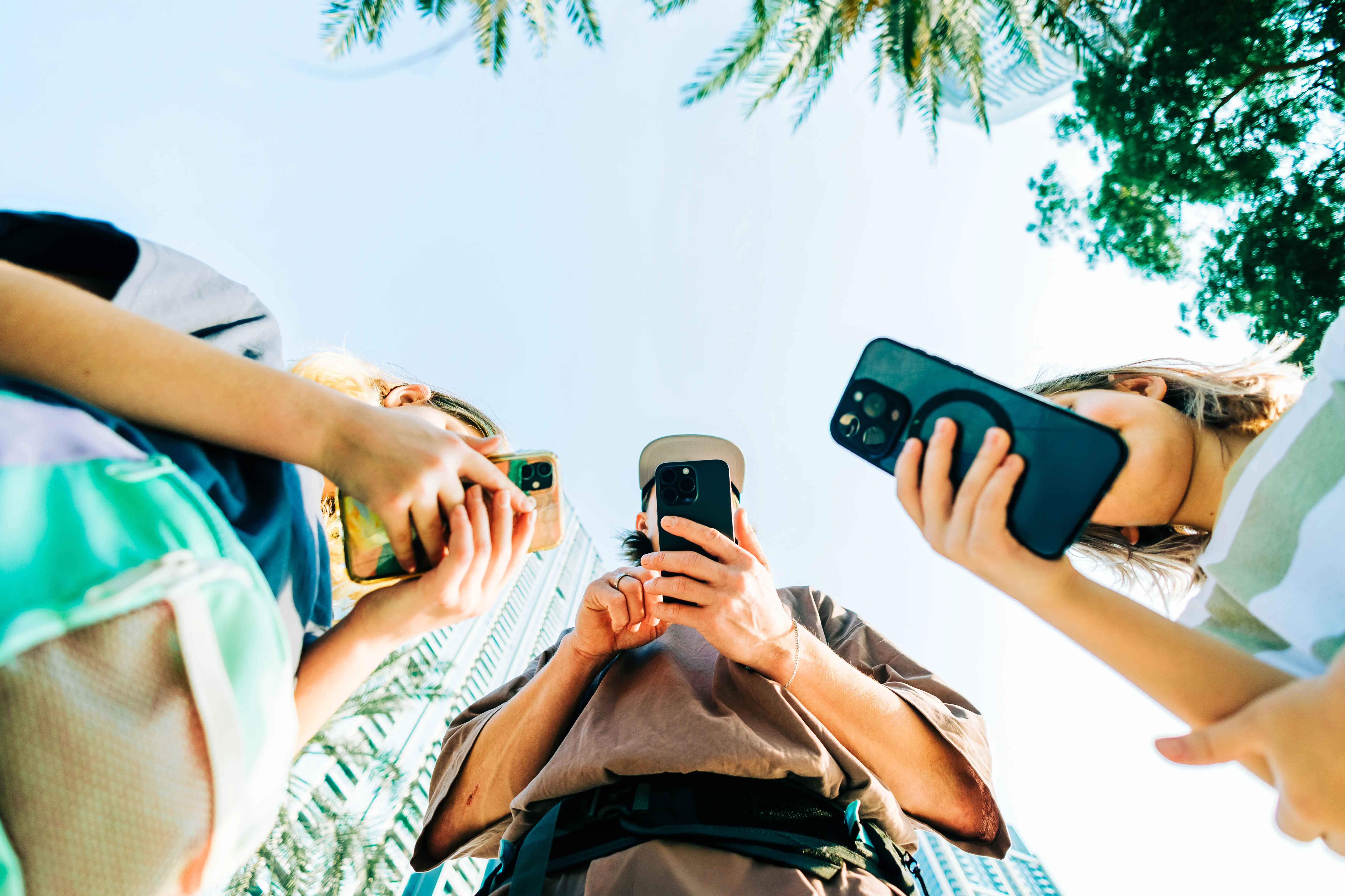 low angle image of three people looking at cell phones