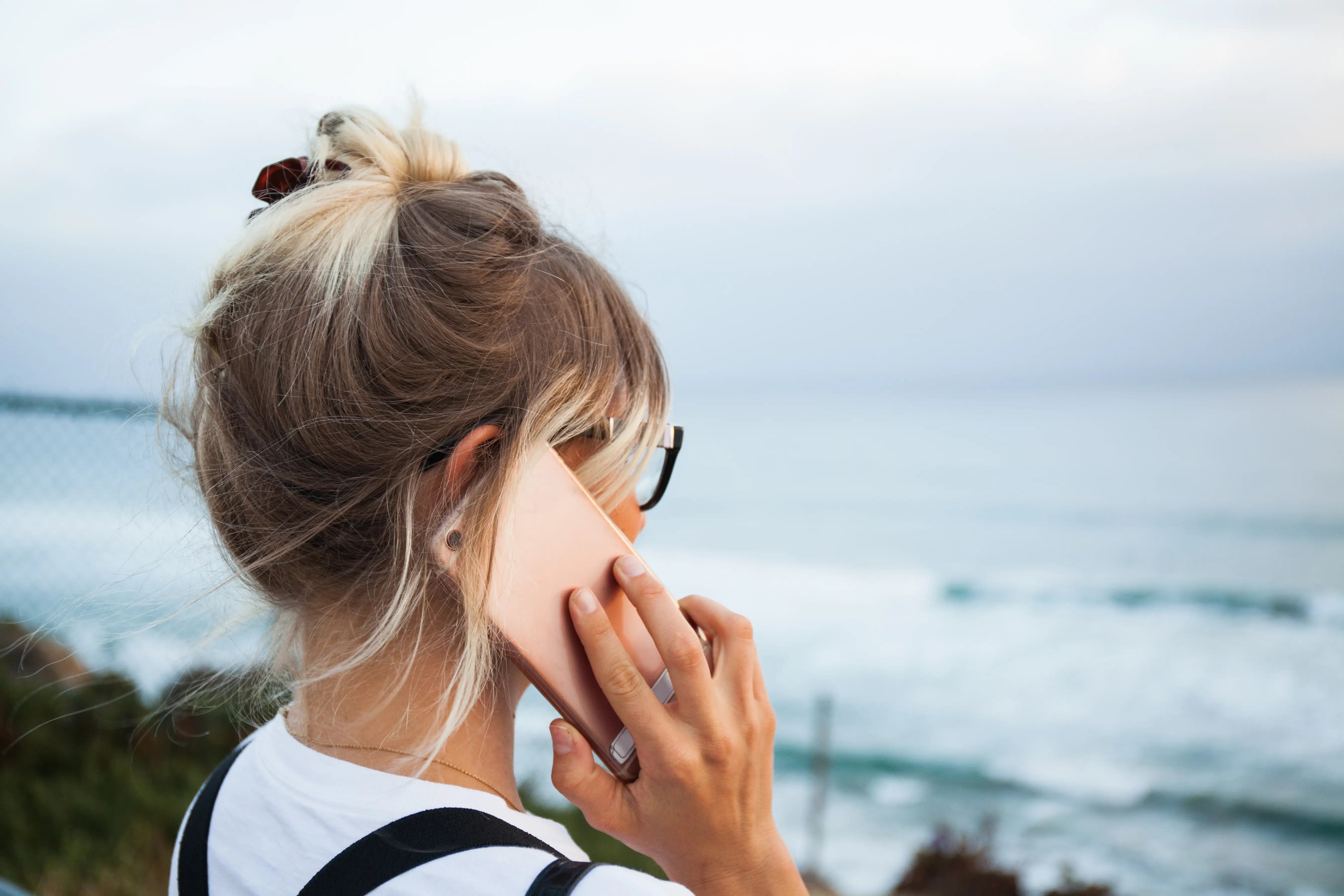 woman talking on phone looking out at ocean