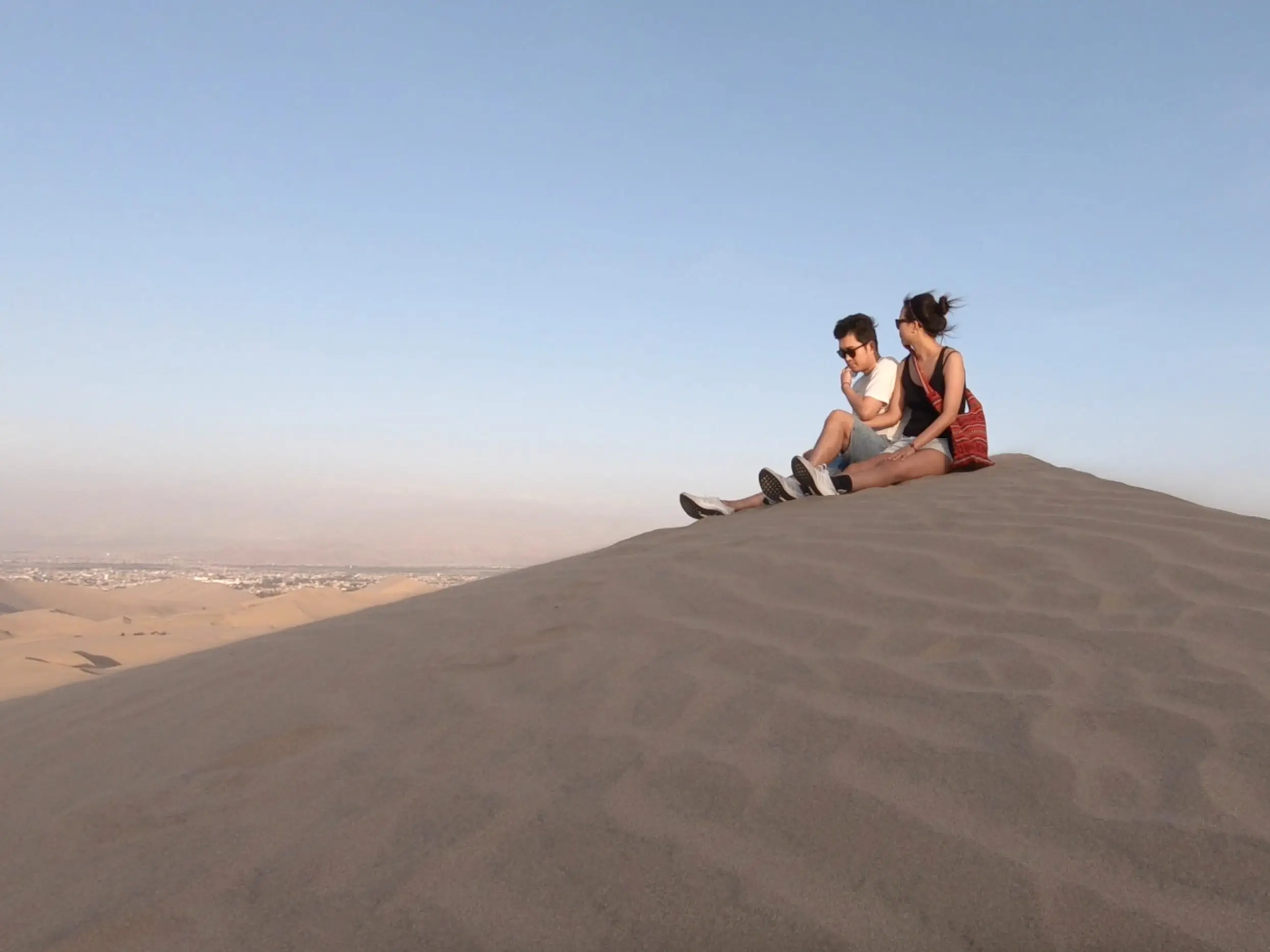 Couple sitting on the sand in a desert.