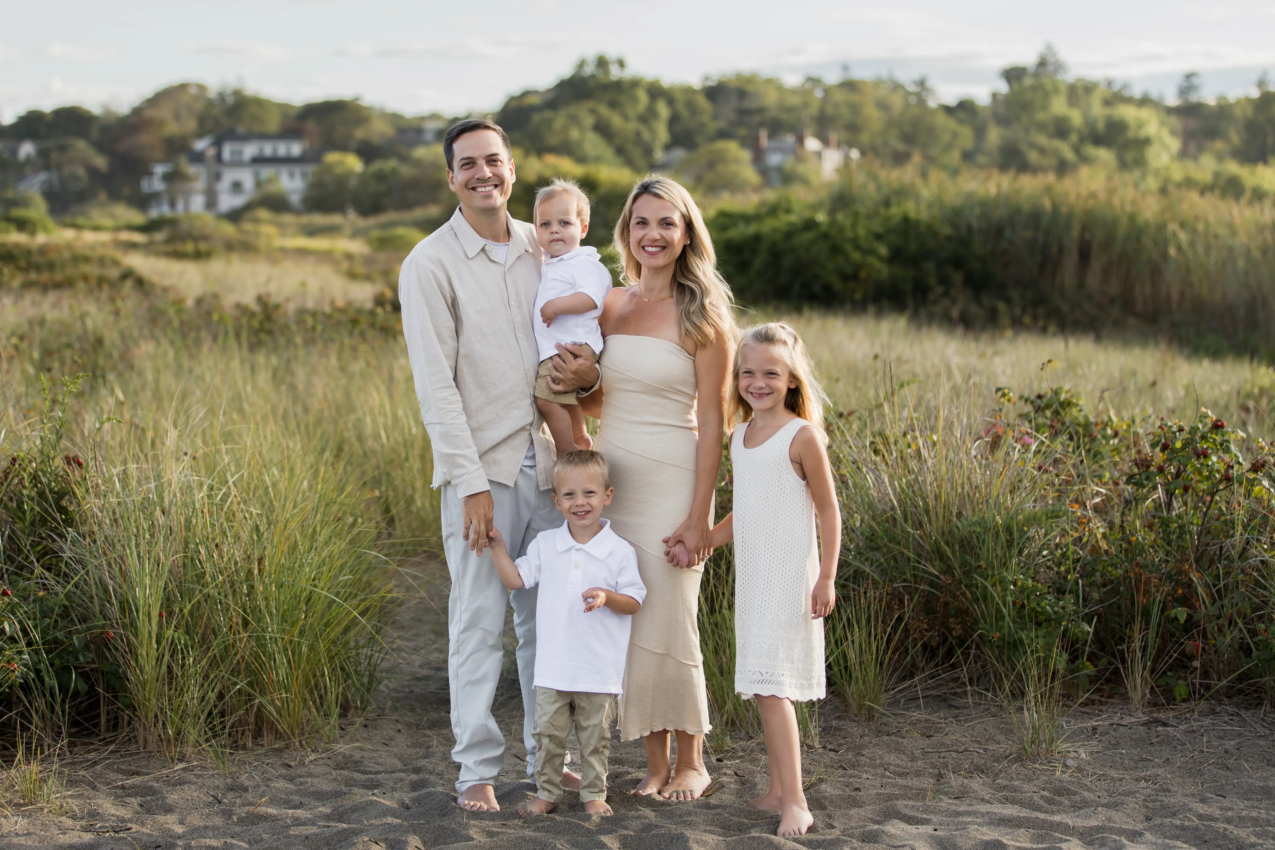 the author, her husband, and three kids standing on dunes at a beach wearing light clothing
