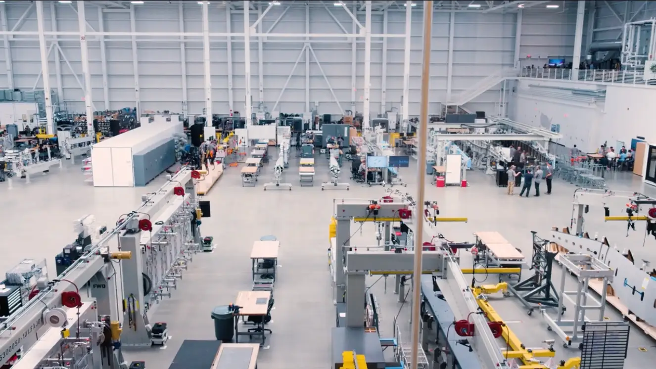 A large white warehouse where Beta Technologies' headquarters are located, filled with machines and assembly lines.