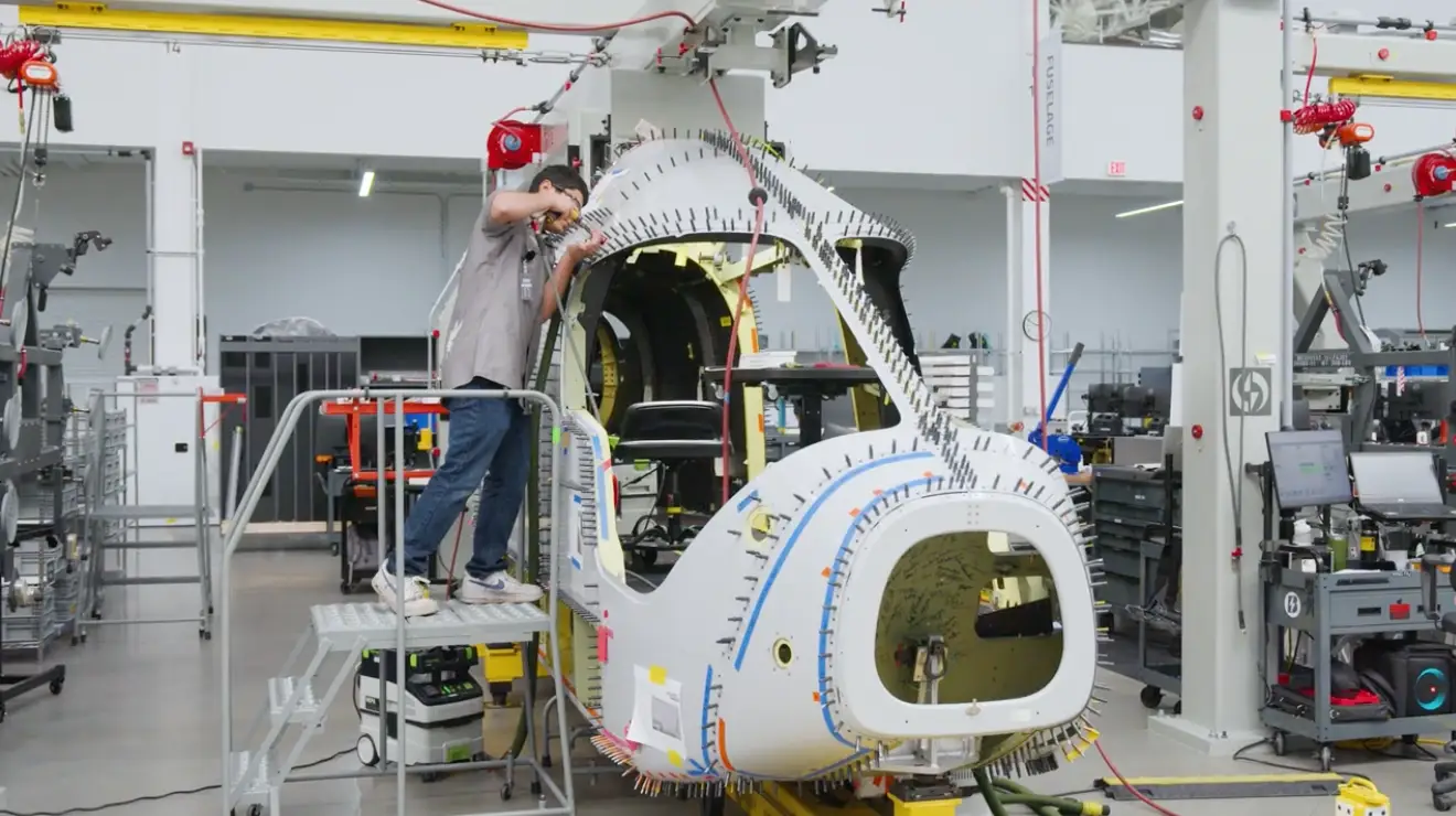 A person inside Beta Technologies warehouse helping build the front segment of a plane.