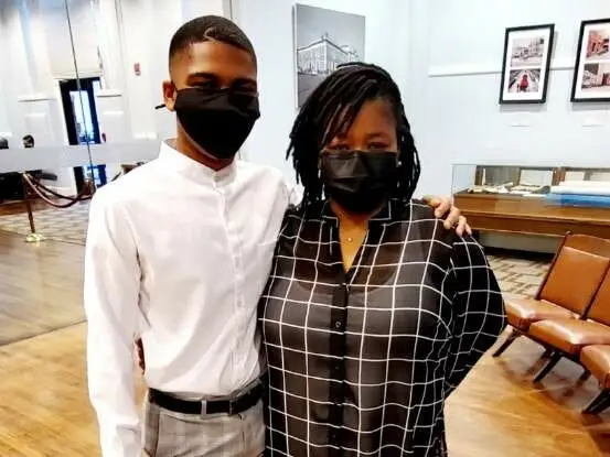 Omarion Calloway and his mother pose together inside a gallery while wearing face masks.