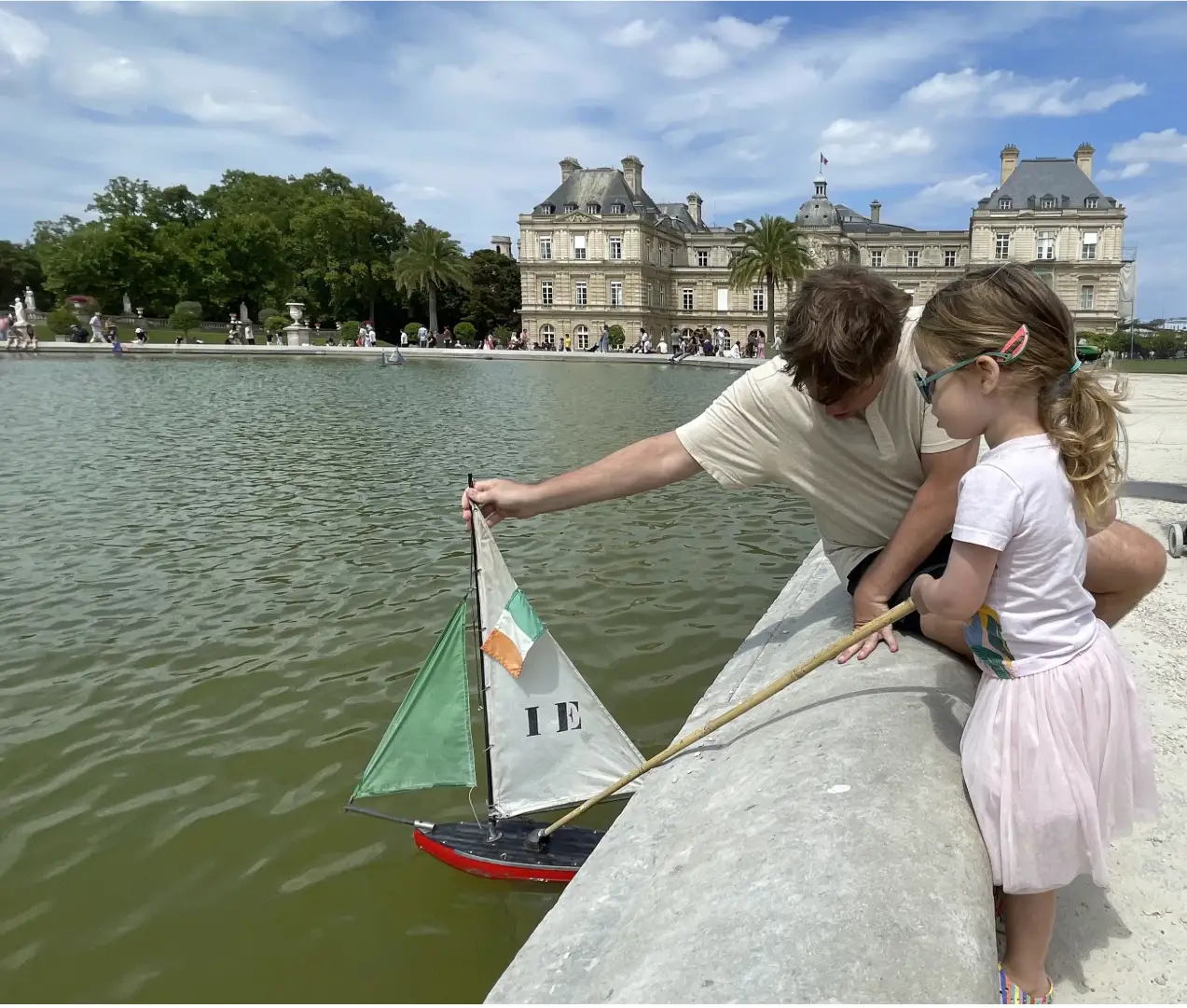 The author's daughter plays with a toy sailboat in the water.