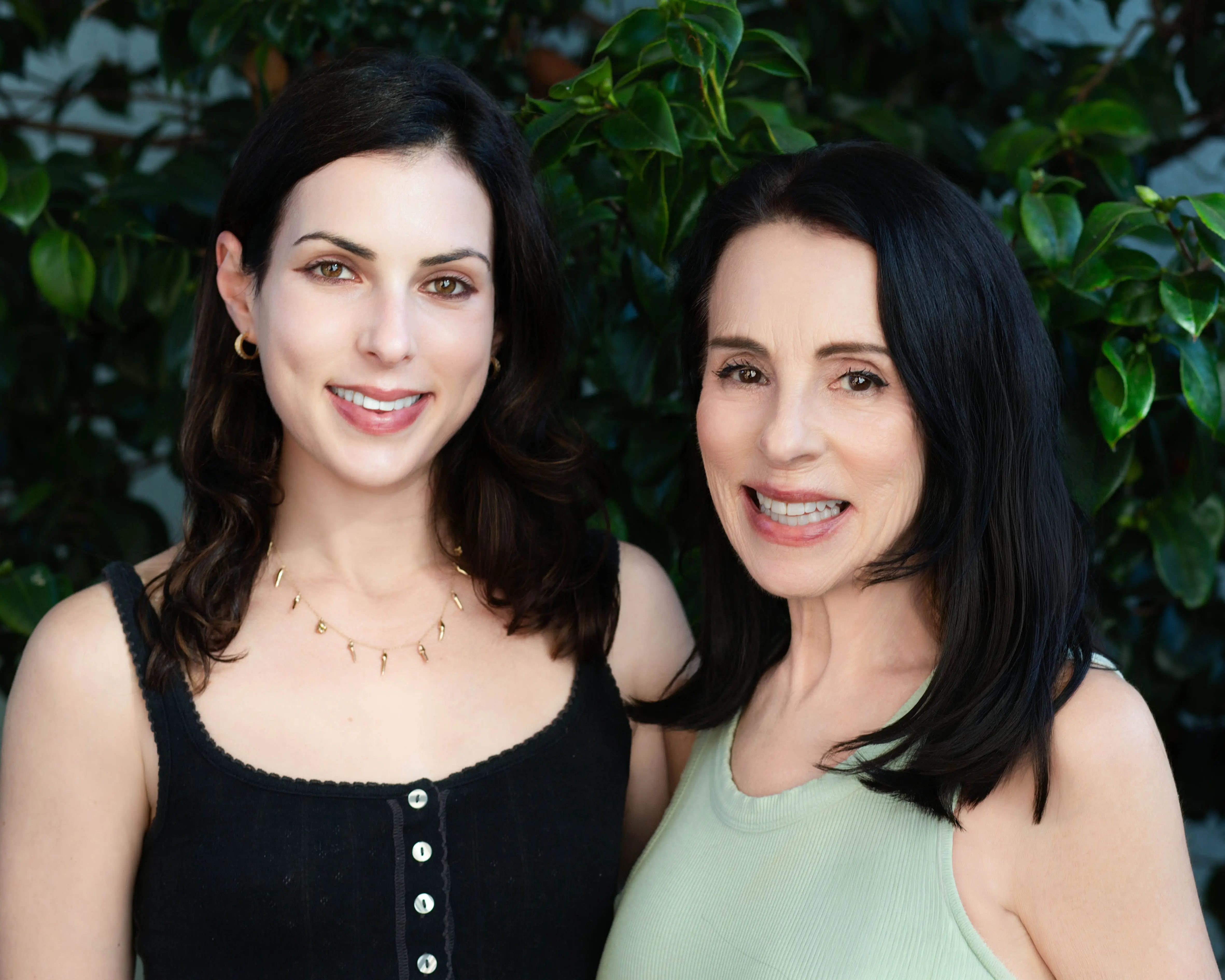 The author (right) and her daughter pose in front of greenery.