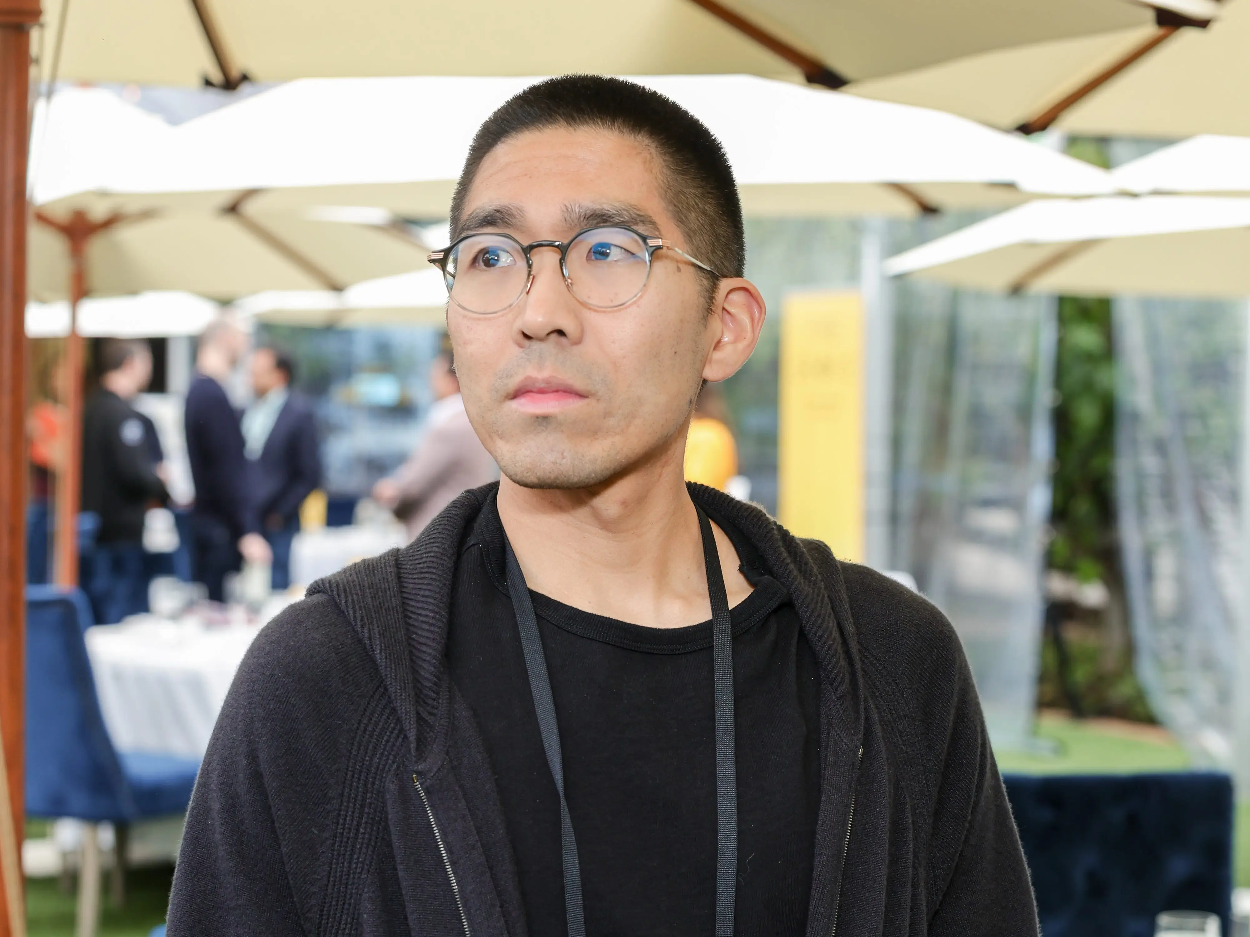 A man in a black hoodie looks off camera.