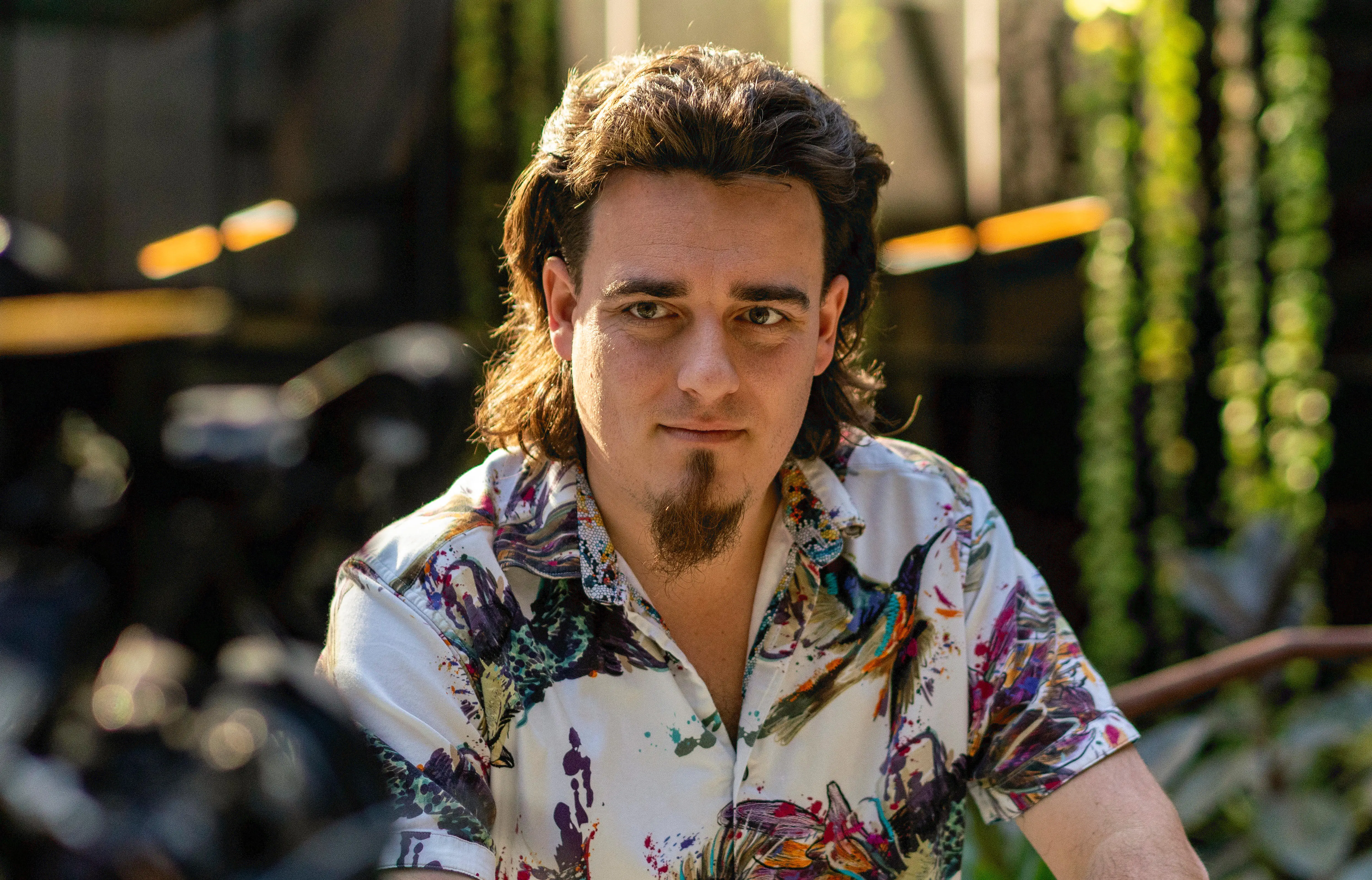 A man in a Hawaiian shirt looks off camera.