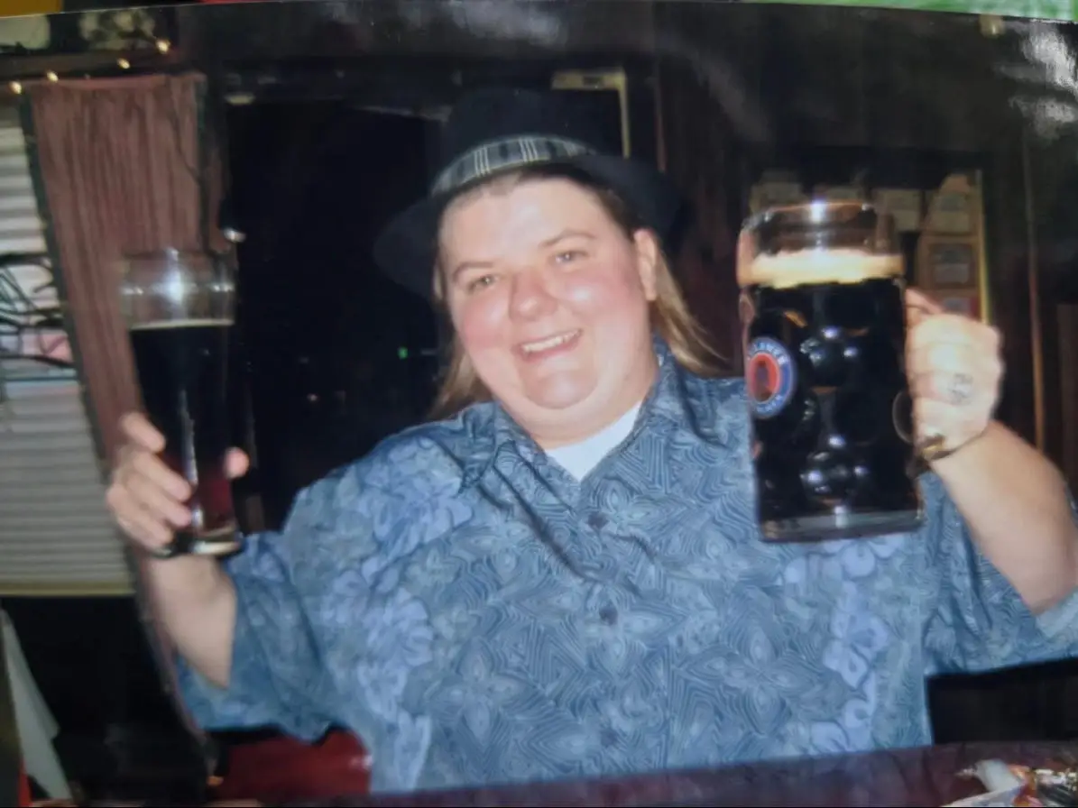 A woman holding up two glasses of beer.
