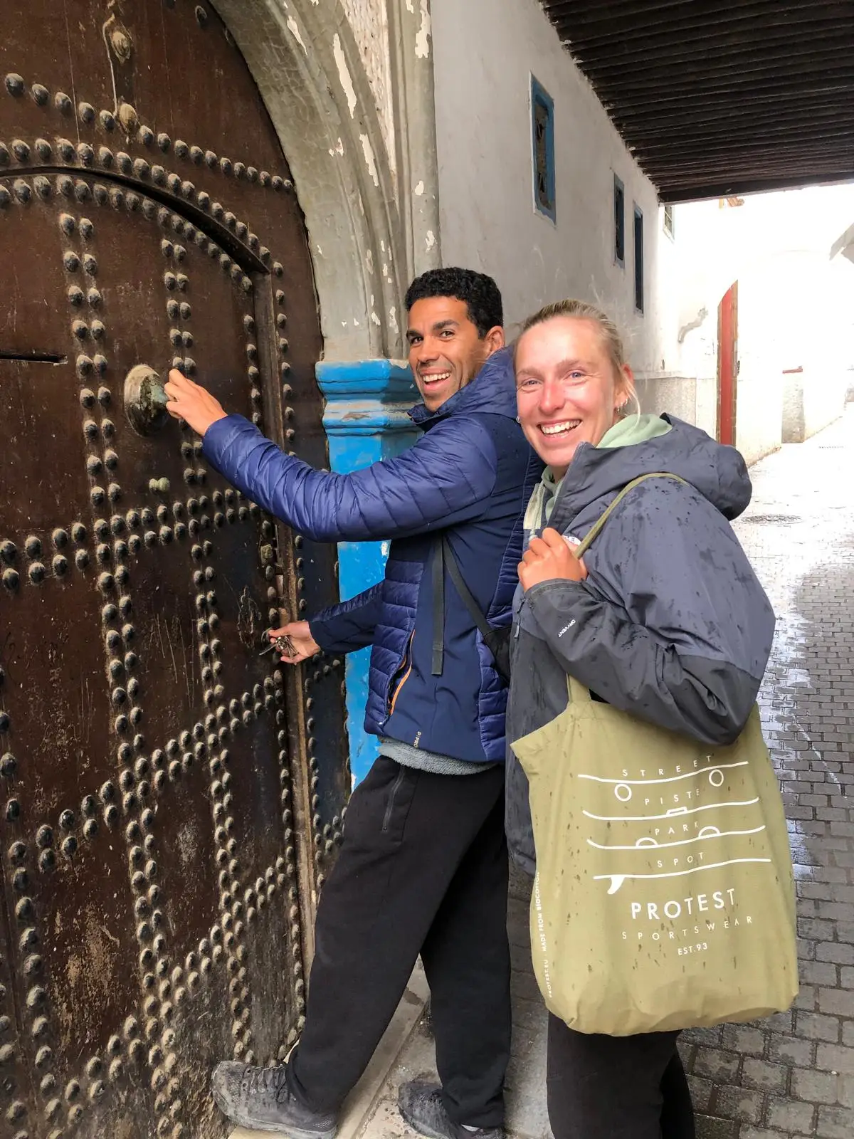 A couple opening the door to a riad, or traditional Moroccan house.