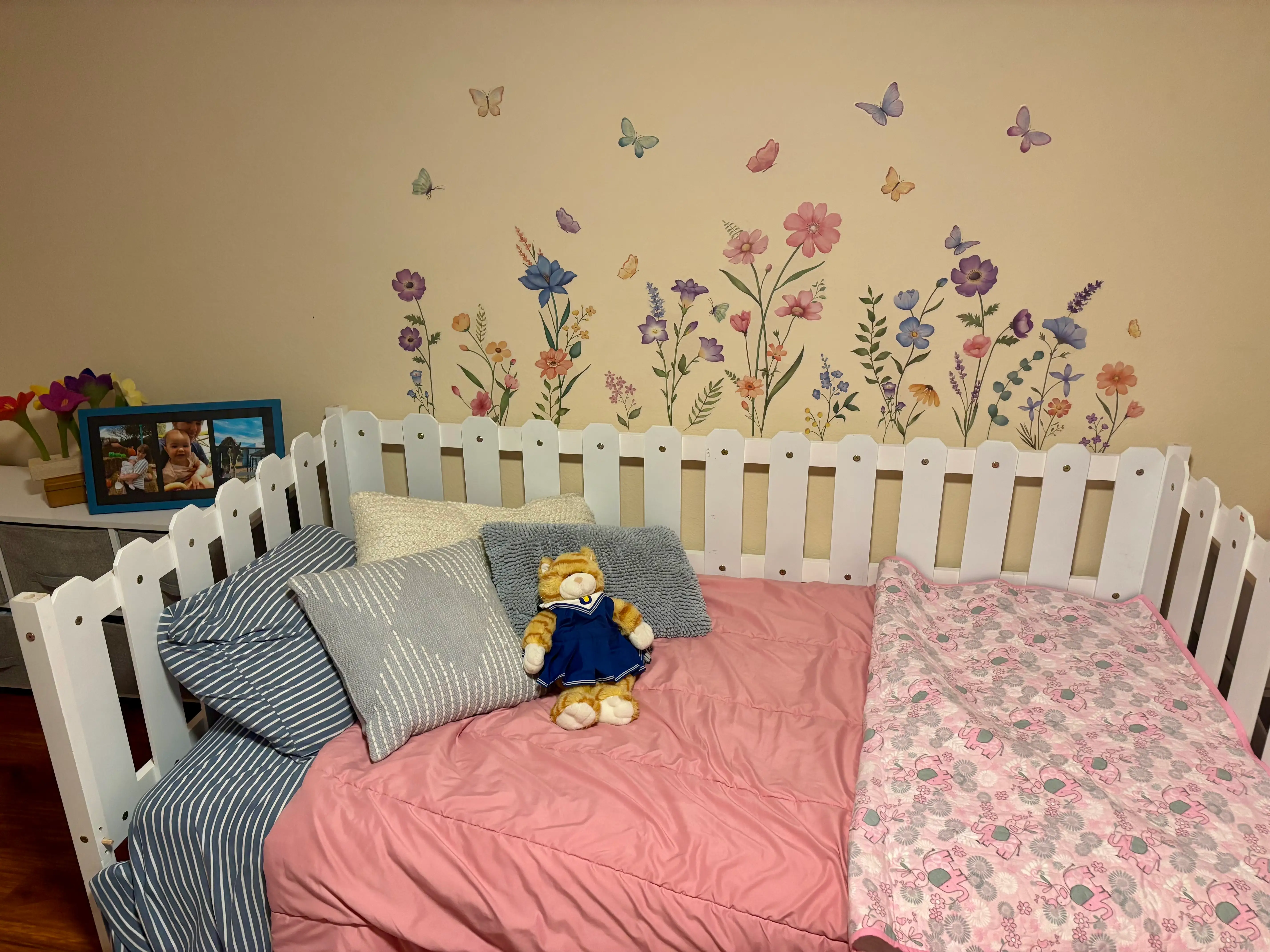 a bed with a frame that looks like a white picket fence and flower decals on the wall