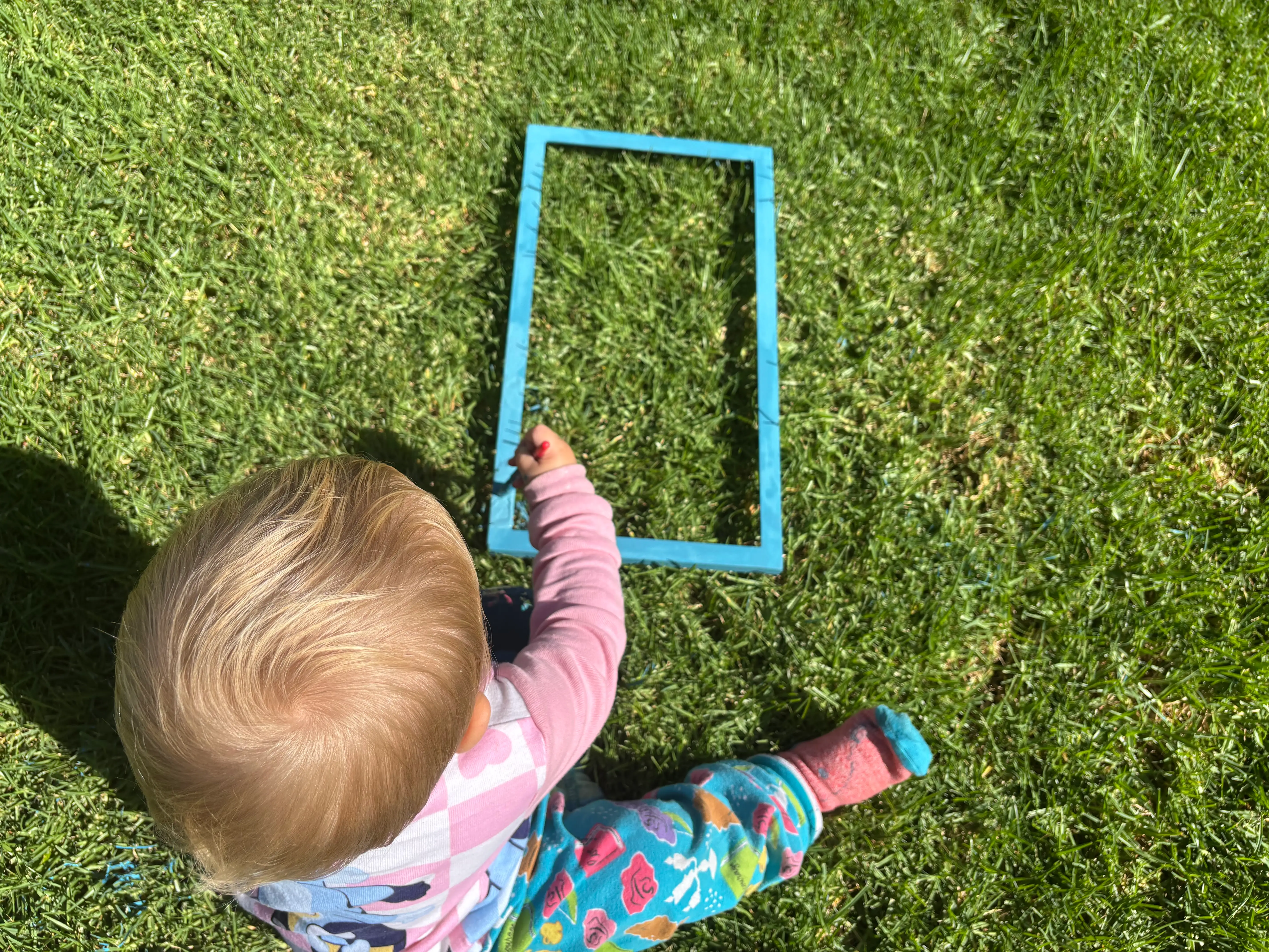 the author's baby painting a picture frame on the grass