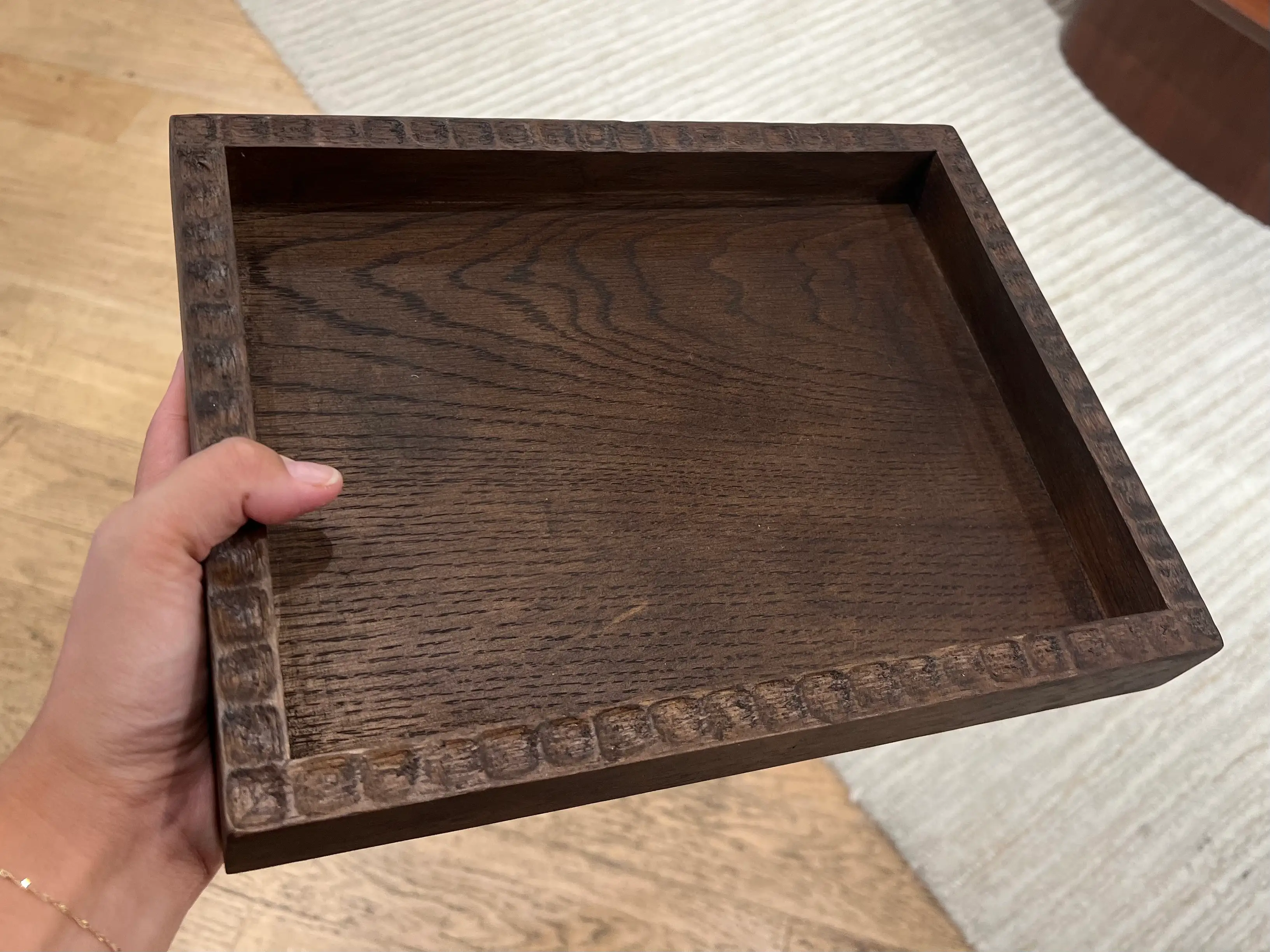 A hand holding a dark-wood tray.