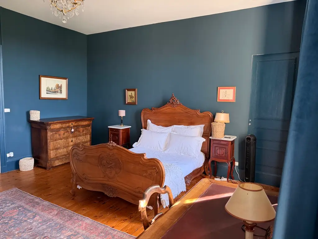 Wooden bed frame, bed in room withblue walls in Etoile Bedroom.