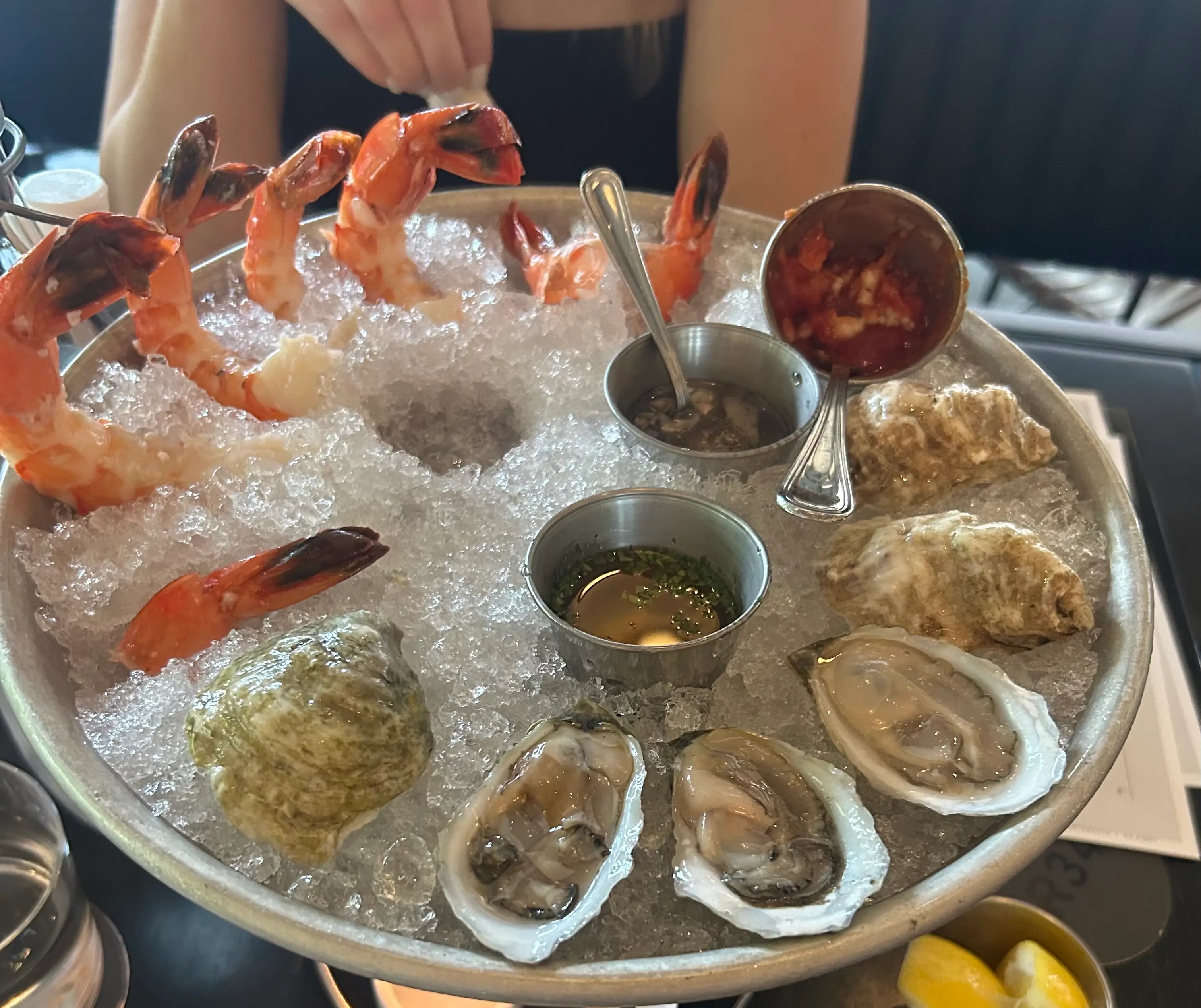 Raw oysters and shrimp cocktail served on crushed ice with sauces and lemon wedges.